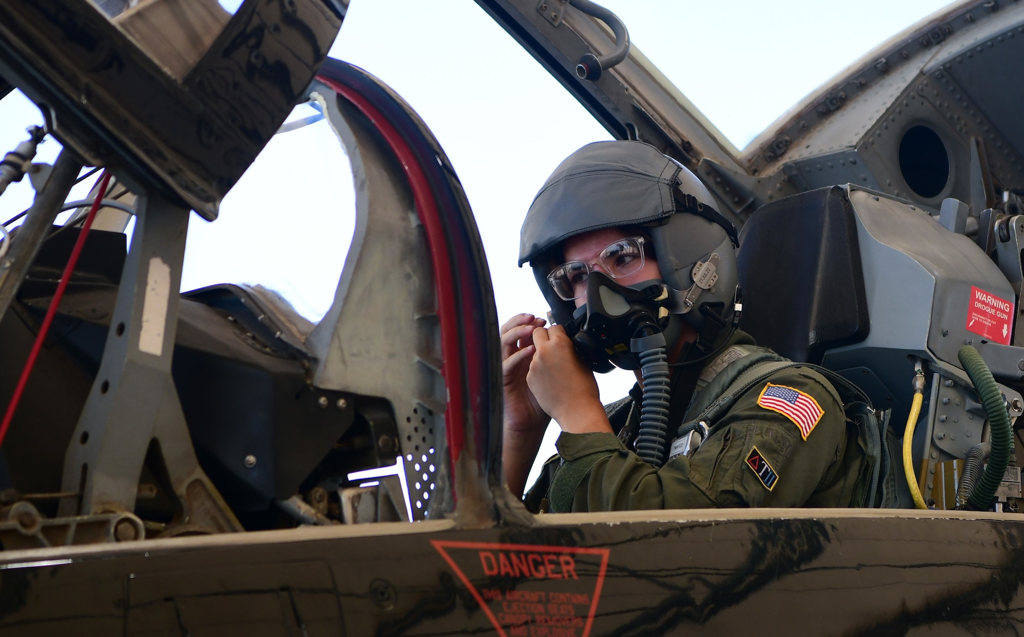 A female Cadet fastens her helmet in a cockpit.