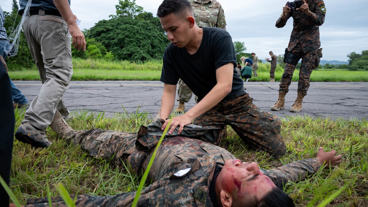 Photo of An El Salvadorian medic (top middle) checking a simulated plane crash survivor (bottom middle) for immediate injuries at Ilopango Air Base, El Salvador, June 16, 2022.