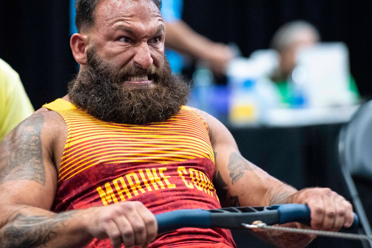 A Marine grimaces while using a row machine.