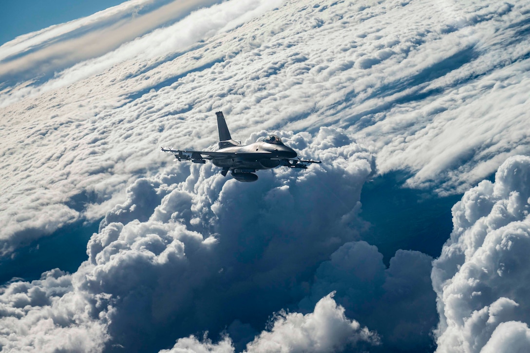 A jet flies above clouds.
