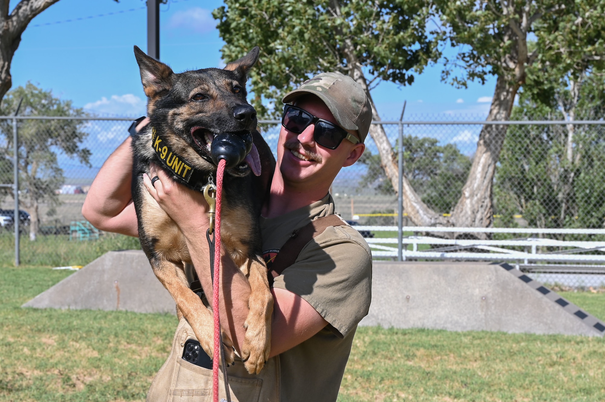 A man holds a dog on his shoulder.