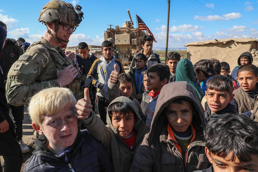 Service members interact with Syrian children.