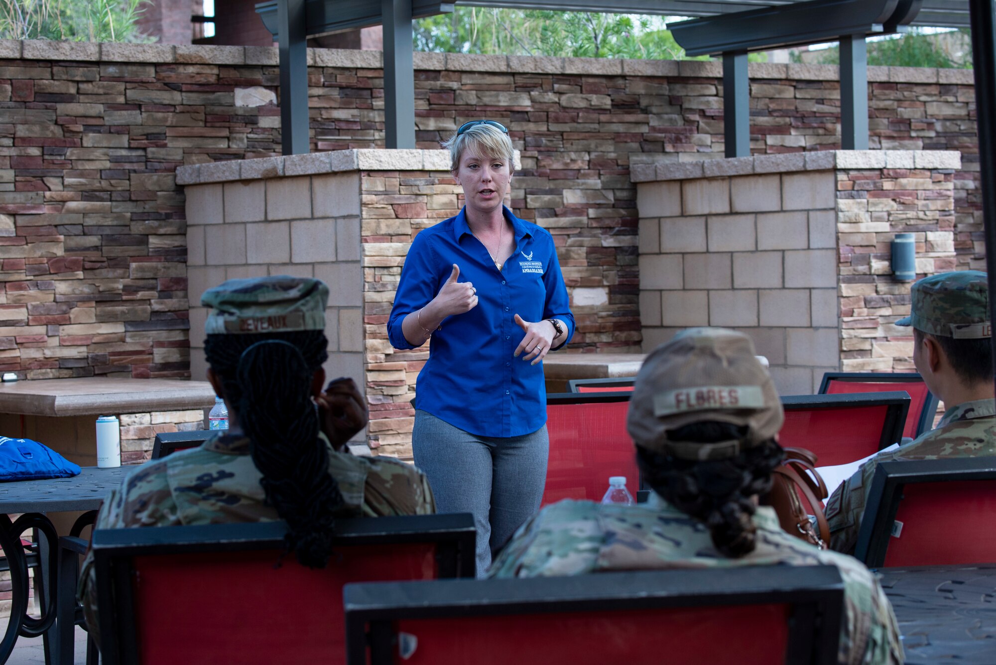 A women in a blue shirt expresses herself to a group of Airmen wearing ocps.