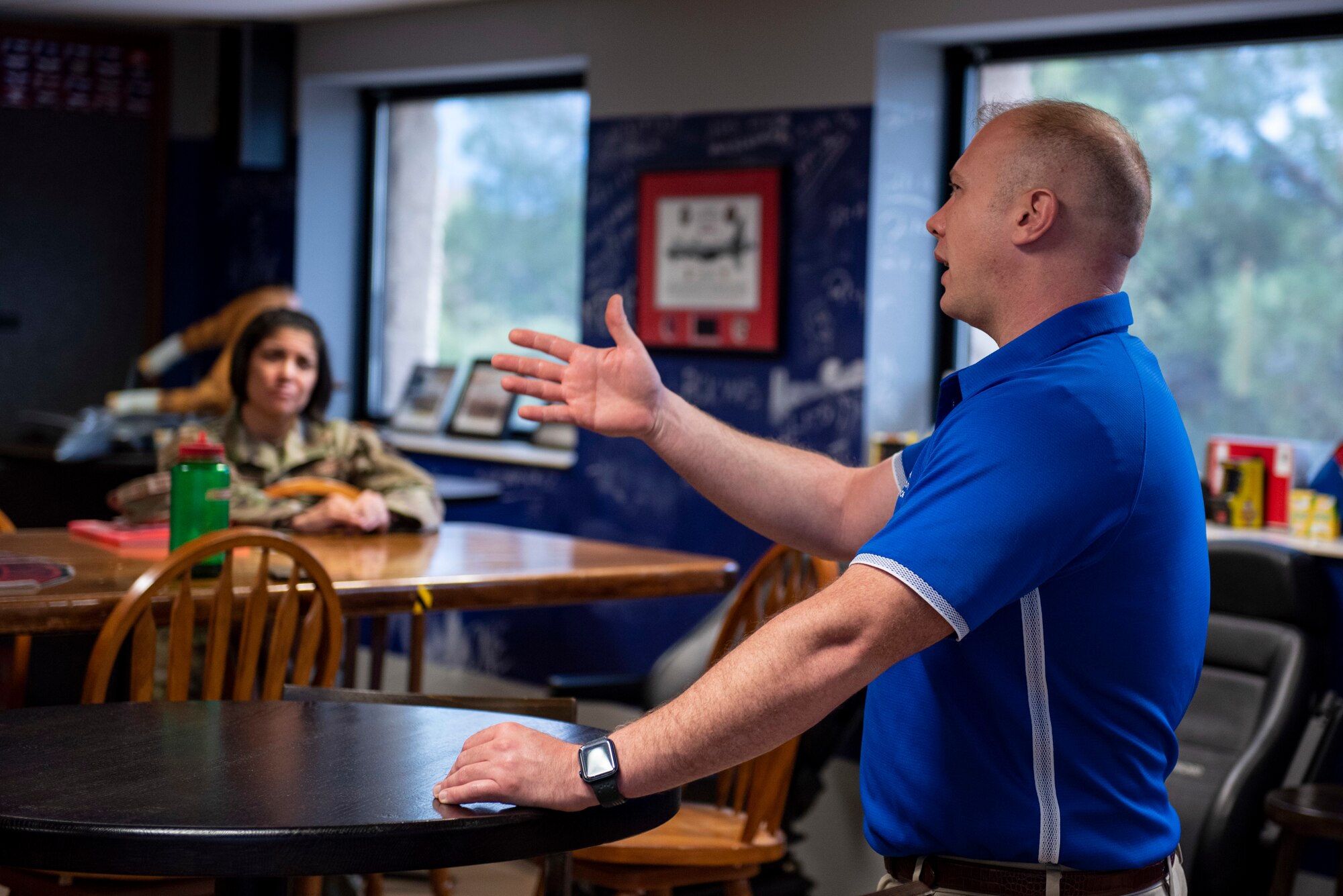 A man in a blue shirt expresses himself to a group of individuals.