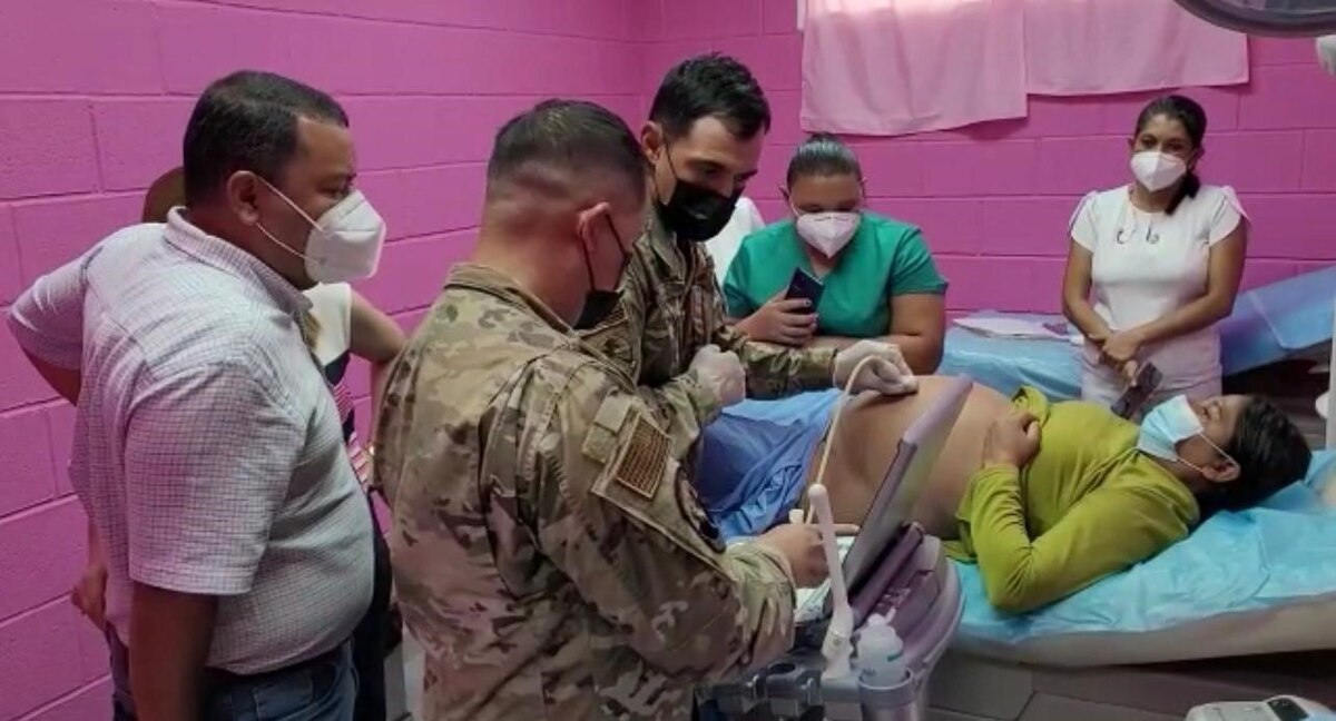 Photo of Master Sgt. Hugo Silva, 819th Rapid Engineer Deployable Heavy Operational Repair Squadron Engineers unit medical advisor, performing an ultrasound on a pregnant patient as Capt. Ryan Mintalar, 60th Operational Medical Readiness Squadron physician assistant, explains the images on the monitor to local medical professionals in Orocuina Honduras, June 29, 2022 as part of a knowledge exchange with healthcare providers during exercise Resolute Sentinel 22.
