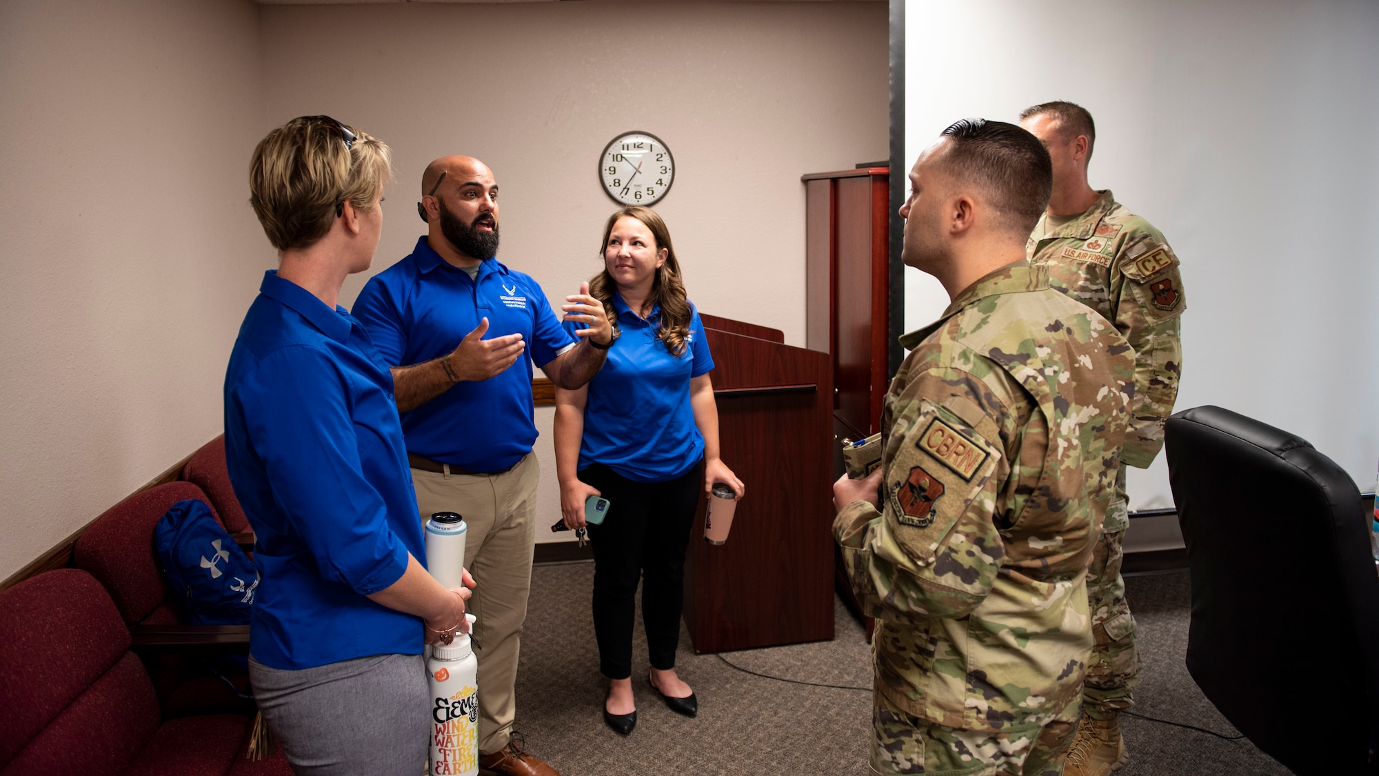 A group of three people in blue shirts explain to two men in ocps what the wounded warrior program is.