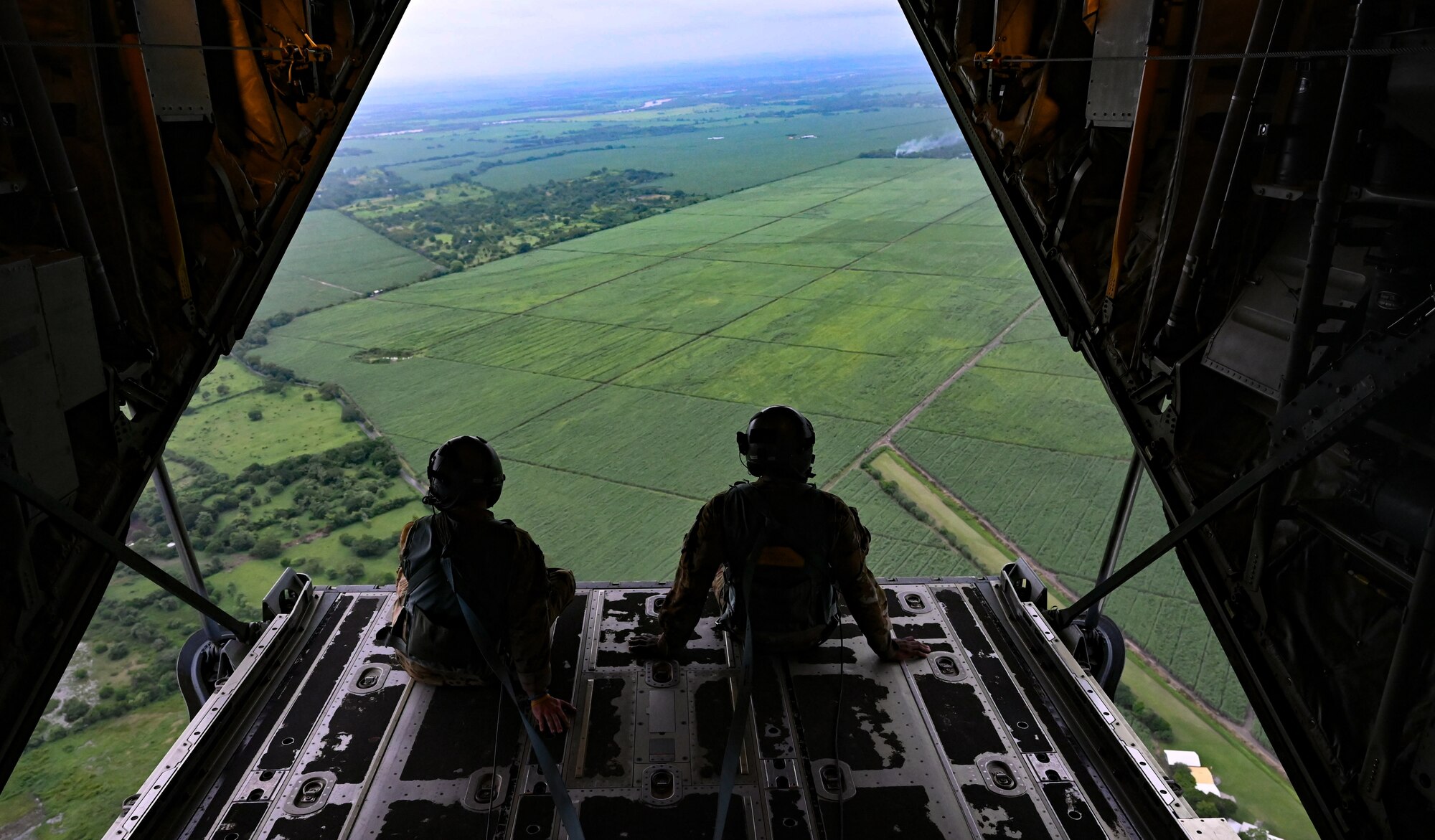 Photo of U.S. Air Force Master Sgt. Gary Bryant and Tech. Sgt. Rocky Menard, both 815th Airlift Squadron loadmasters, looking out the back of a C-130J Super Hercules over Guatemala, prior to static line operations as part of Resolute Sentinel 22, June 15, 2022.