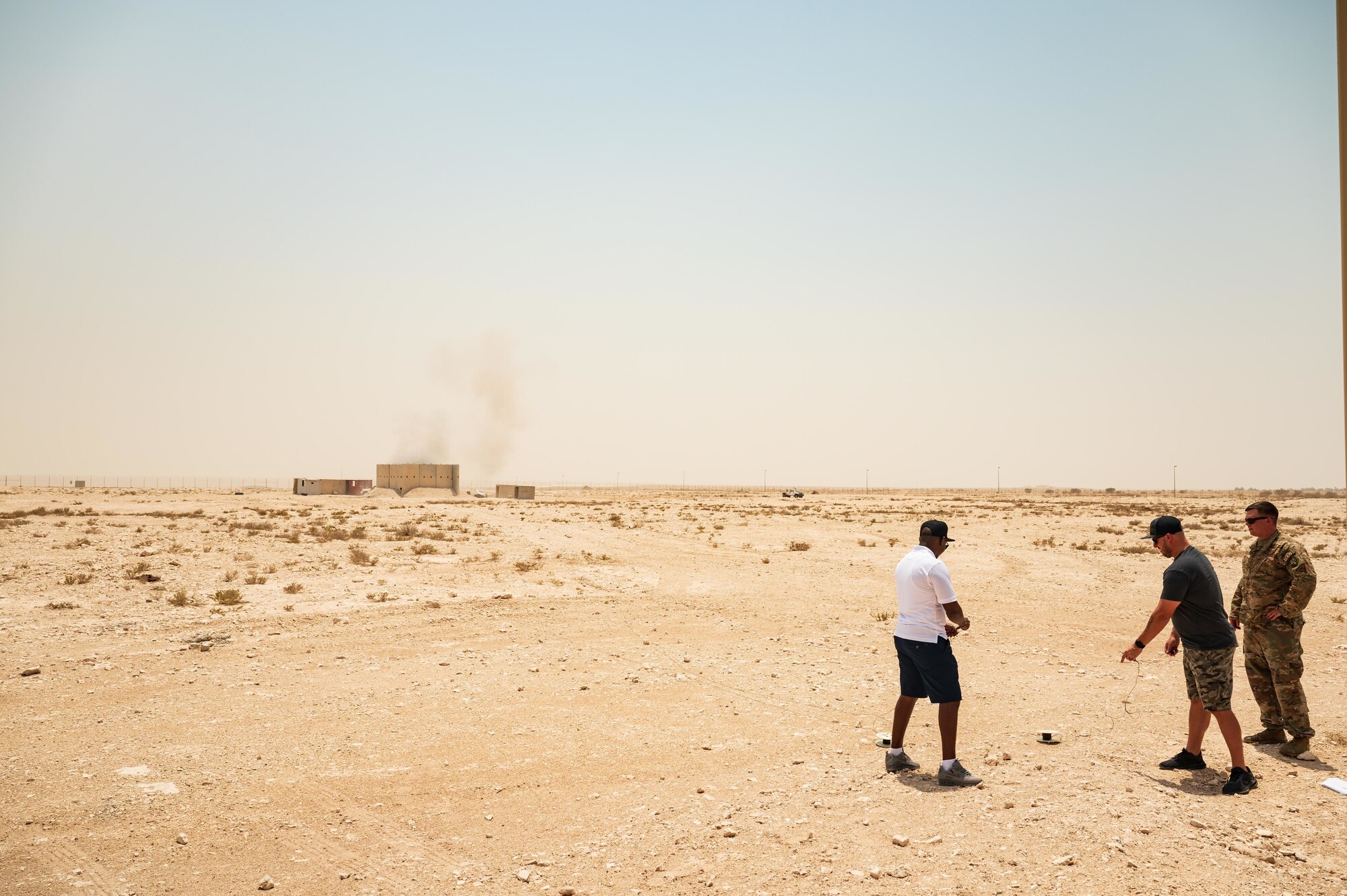 U.S. Air Force Tech Sgt. Penn Lillie (right), an explosive ordinance disposal team leader, 379th Expeditionary Civil Engineer Squadron watches as the fuse is triggered by one of the Comedy Brigade members during a live demonstration at Al Udeid Air Base, Qatar, AUG 8, 2022. The comedians were able to set off the charges during the demo. (U.S. Air Force photo by Staff Sgt. Dana Tourtellotte)