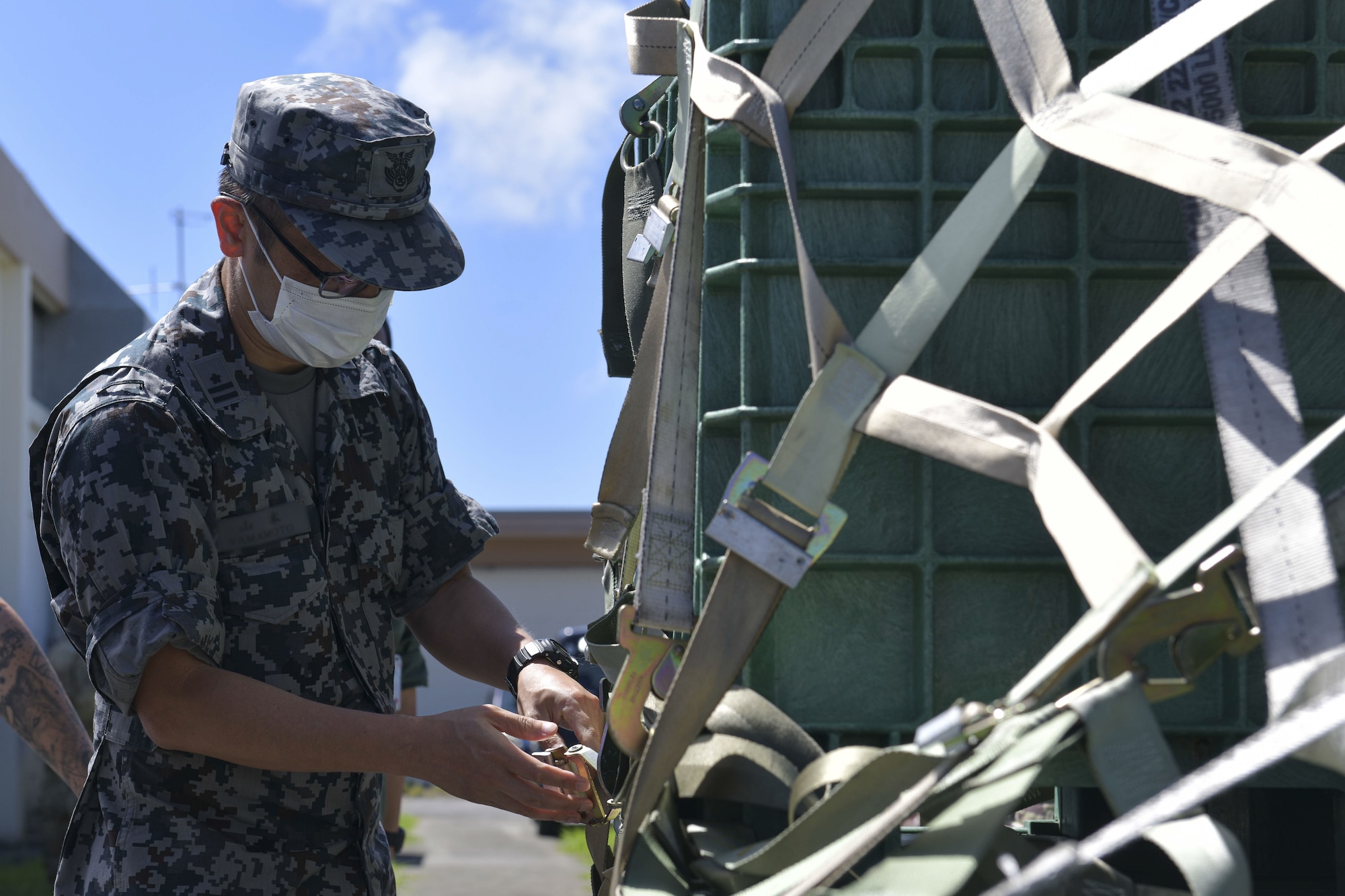 A Japanese military member adjusts some straps on a package