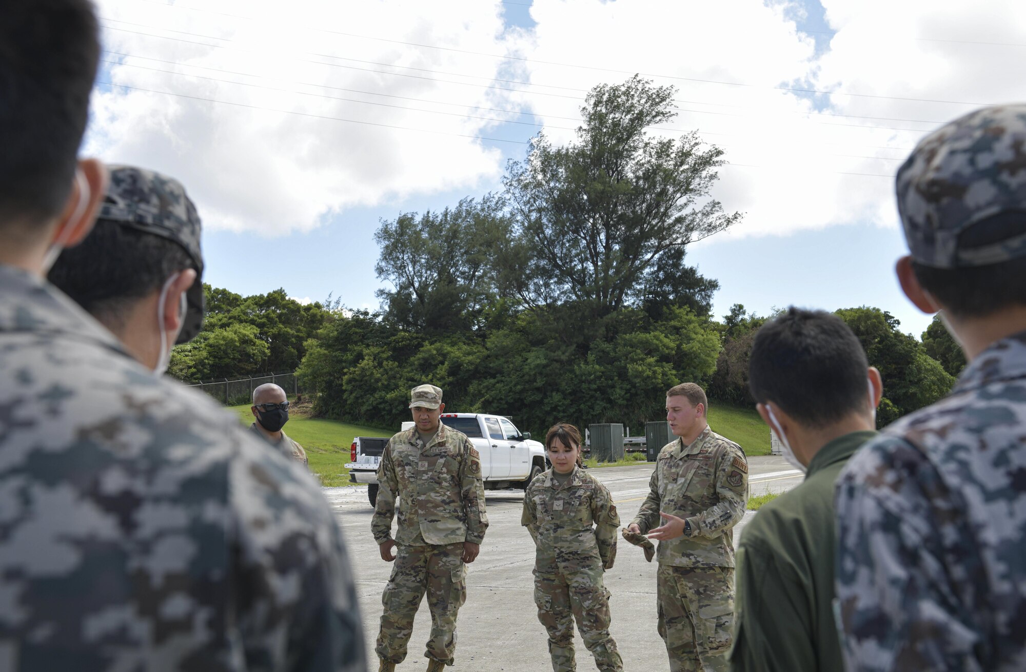 Japanese military personnel listen to explanations on how to patch airfields quickly from U.S. Military personnel