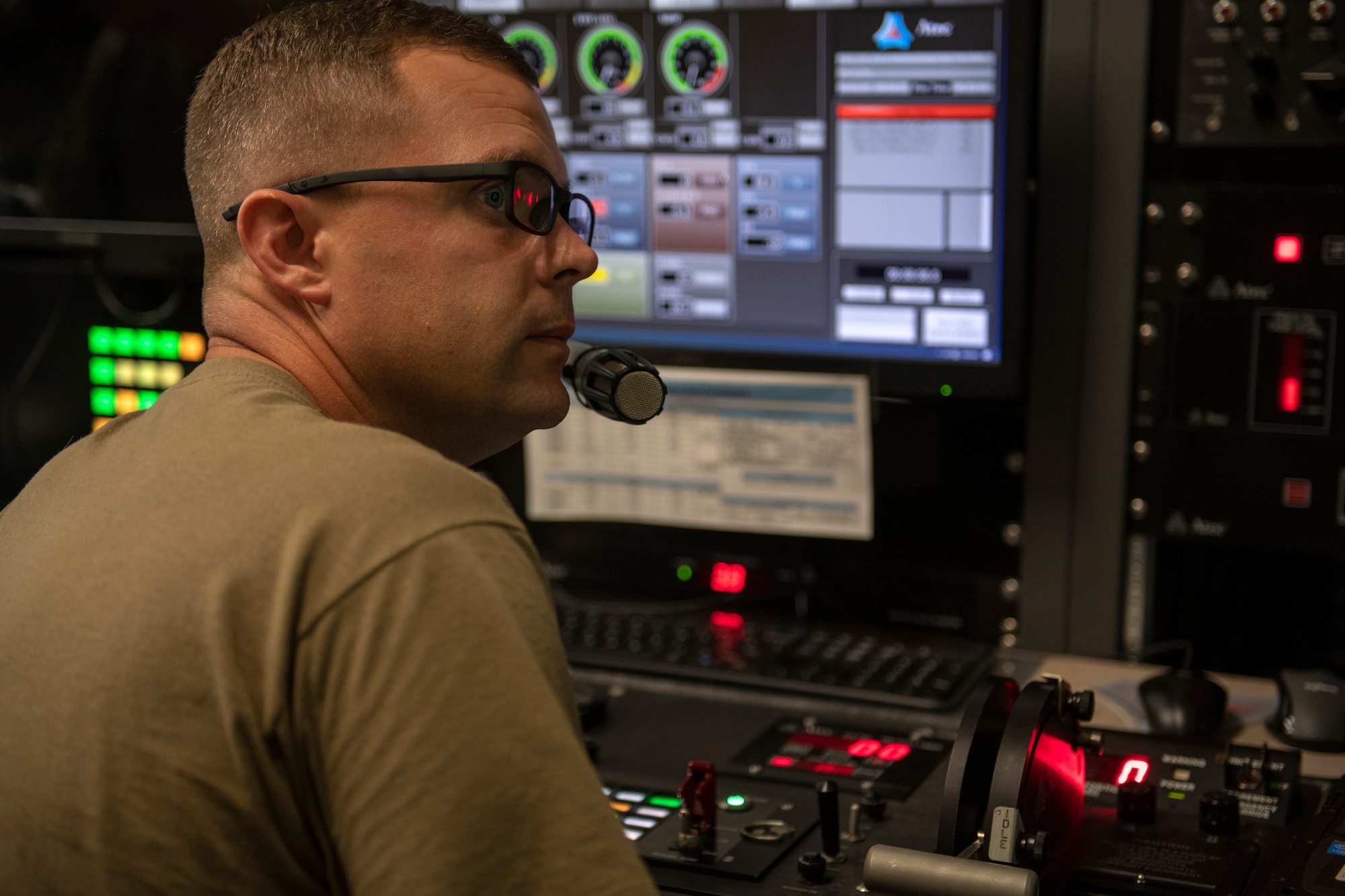 U.S. Air Force Staff Sgt. Dustin Chapman, 18th Component Maintenance Squadron test cell craftsman, maintains visual and verbal communication with the Airman inside the test cell at Kadena Air Base, Japan, Aug. 25, 2022. The control booth operator records all engine parameters during the run. The recorded information is used for troubleshooting future engine runs and keeping track of trending data. (U.S. Air Force photo by Senior Airman Jessi Roth)