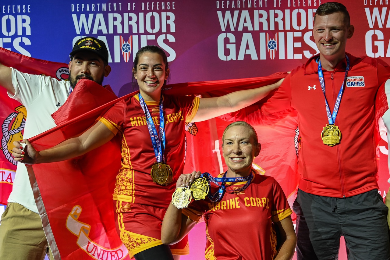 A group of athletes pose with medals and flags.