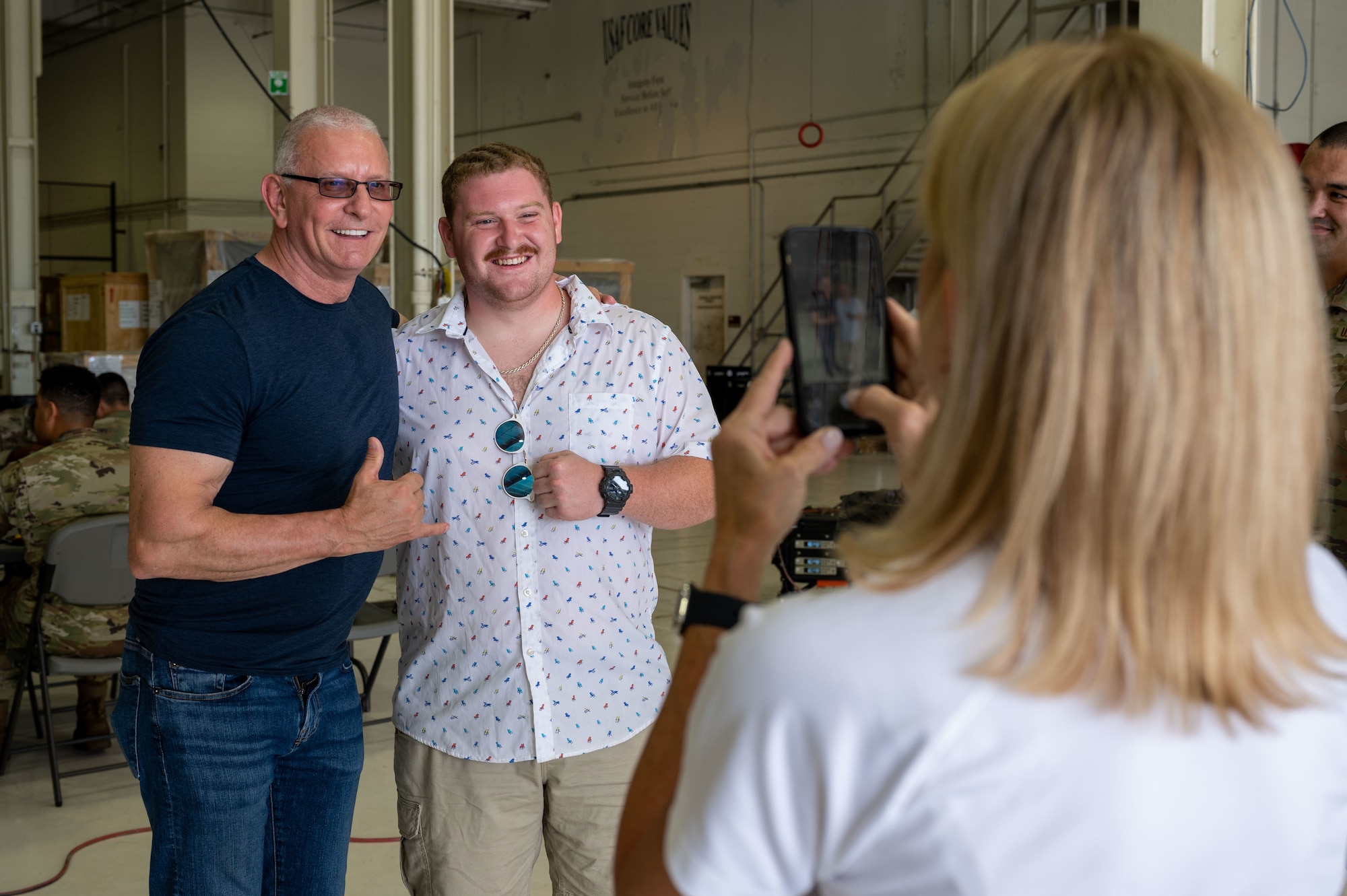 Senior Airman Clint Helgoth, middle, 436th Logistics Readiness Squadron fuels distribution operator, poses with Robert Irvine during the Meet, Greet, Eat with Chef Robert Irvine event on Dover Air Force Base, Delaware, Aug. 25, 2022. More than 75 Airmen attended the event which included a photo opportunity with Irvine and a catered lunch. (U.S. Air Force photo by Senior Airman Cydney Lee)