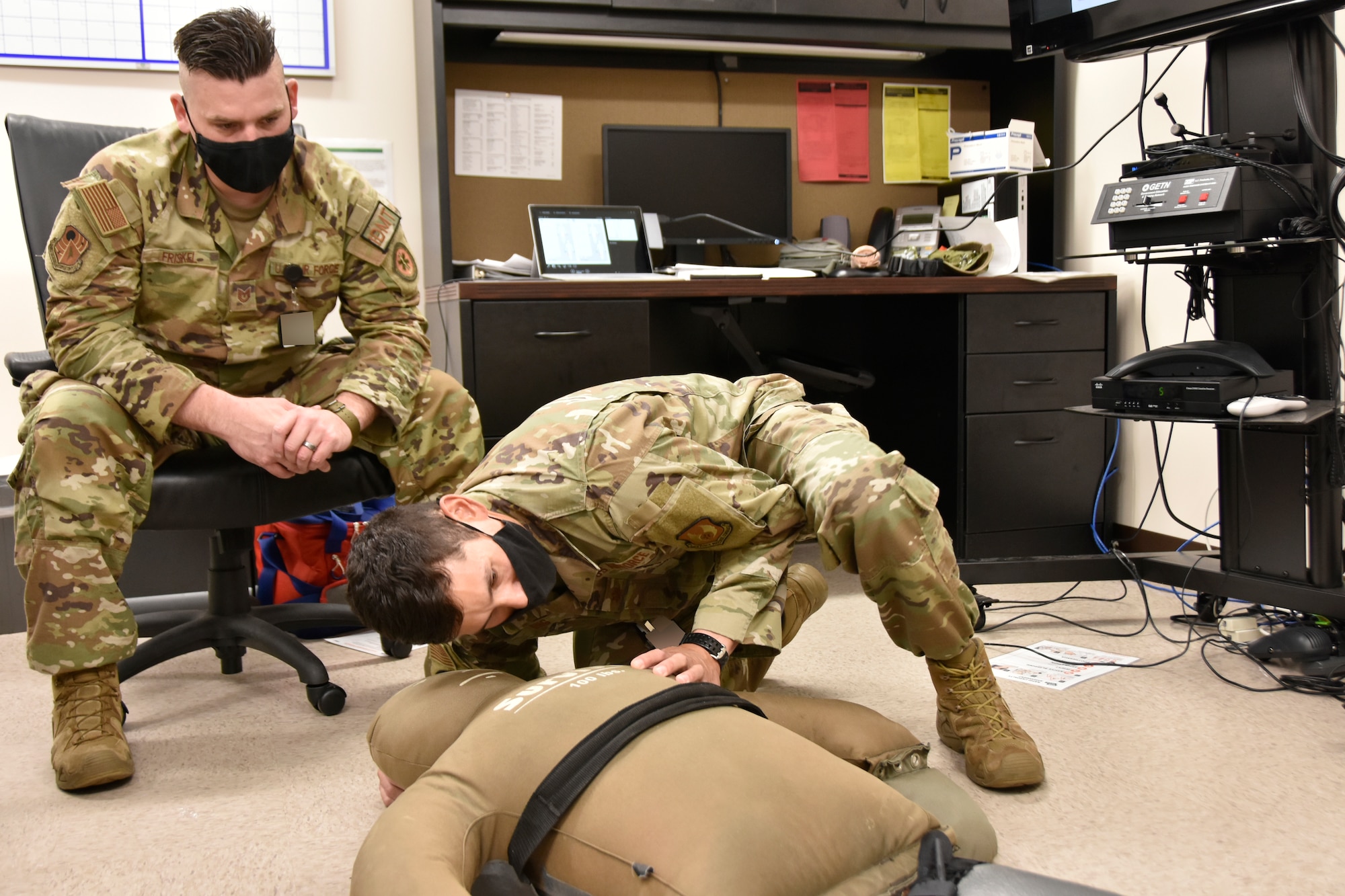 Tech. Sgt. Mark Friskel, an independent duty medical technician at Arnold Air Force Base, Tennessee, left, looks on as Maj. Justin Ong checks a simulated victim for breathing during Tactical Combat Casualty Care training Aug. 15, 2022, at the Arnold AFB Medical Aid Station. TCCC trainees are taught lifesaving techniques, strategies and procedures, allowing those who have been trained to provide best practice trauma care both on and off the battlefield. Ong was part of the first TCCC class, instructed by Friskel, at Arnold. The first level of TCCC training is required by all Department of Defense service members by April 2023. (U.S. Air Force photo by Bradley Hicks) (This image was altered by obscuring badges for security purposes)