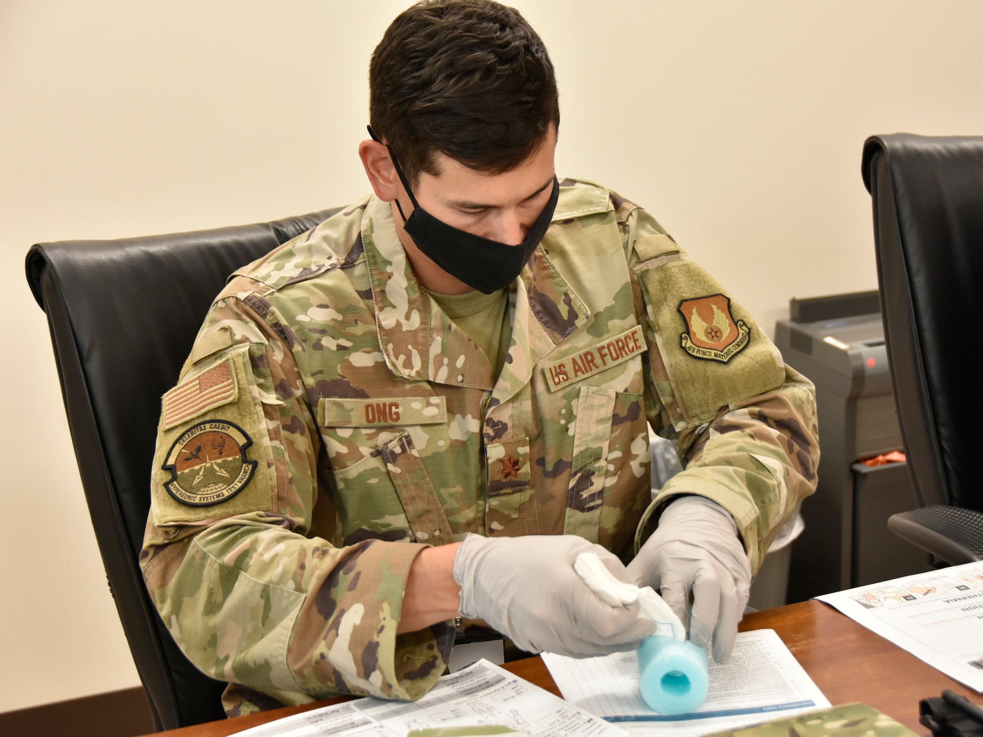 Maj. Justin Ong uses a pool noodle to practice wound packing during Tactical Combat Casualty Care training Aug. 15, 2022, at the Medical Aid Station at Arnold Air Force Base, Tennessee. The pool noodle represents a massive bleeding injury requiring immediate care. TCCC trainees are taught lifesaving techniques, strategies and procedures, allowing those who have been trained to provide best practice trauma care both on and off the battlefield. Ong was part of the first TCCC class at Arnold. The first level of TCCC training is required by all Department of Defense service members by April 2023. (U.S. Air Force photo by Bradley Hicks) (This image was altered by obscuring a badge for security purposes)