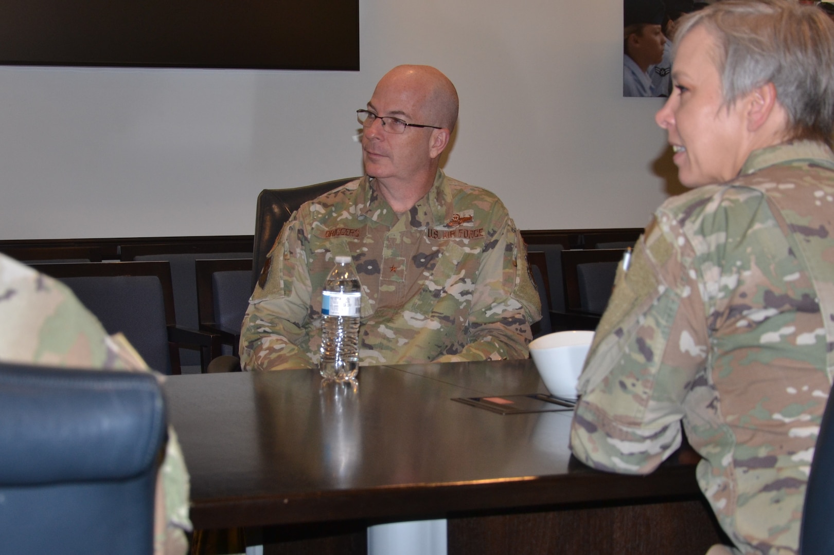 Military general sitting at table listening to others speak.