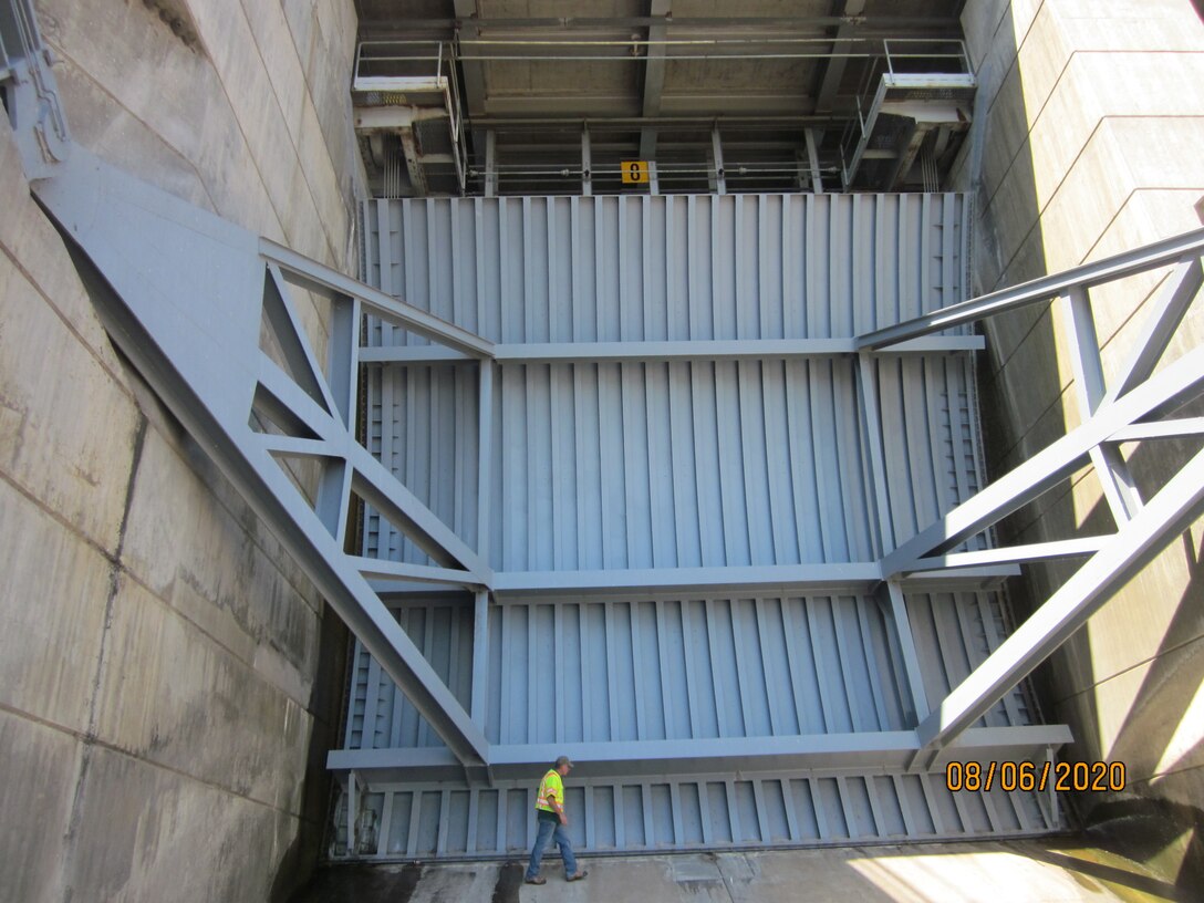 A person in a yellow top walks in front of a large metal door