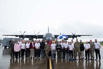 civic leaders pose for a group photo in front of an AC-130J aircraft.