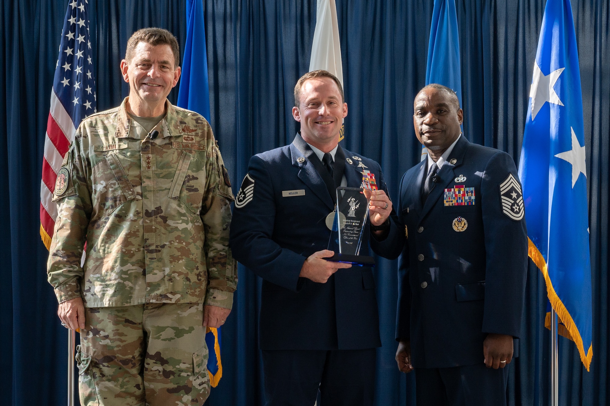 U.S. Air Force Master Sgt. Daniel P. Keller, of the 124th Fighter Wing, Idaho National Guard, poses for a photo with Lt. Gen. Michael A. Loh, left, director, Air National Guard (ANG), and Chief Master Sgt. Maurice L. Williams, right, command chief, ANG, during the Outstanding Airmen of the Year ceremony at Joint Base Andrews, Maryland, on Aug. 25, 2022.