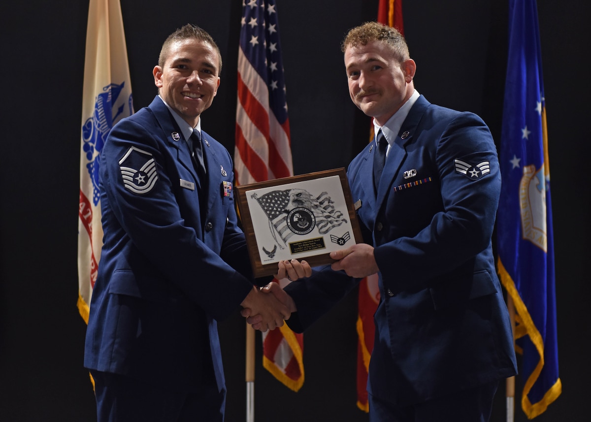 U.S. Air Force Master Sgt. Donald Kramer, 312th Training Squadron Special Instruments Training instructor supervisor, presents Senior Airman Dylan Servis, 47th Operations Support Squadron aircrew flight equipment specialist, the Academic Achievement award during the Airman Leadership School graduation at the Powell Event Center, Goodfellow Air Force Base, Texas, Aug. 26, 2022. The Academic Achievement award recognizes an airman who demonstrated superior academic performance during the five-week course. (U.S. Air Force photo by Airman 1st Class Sarah Williams)