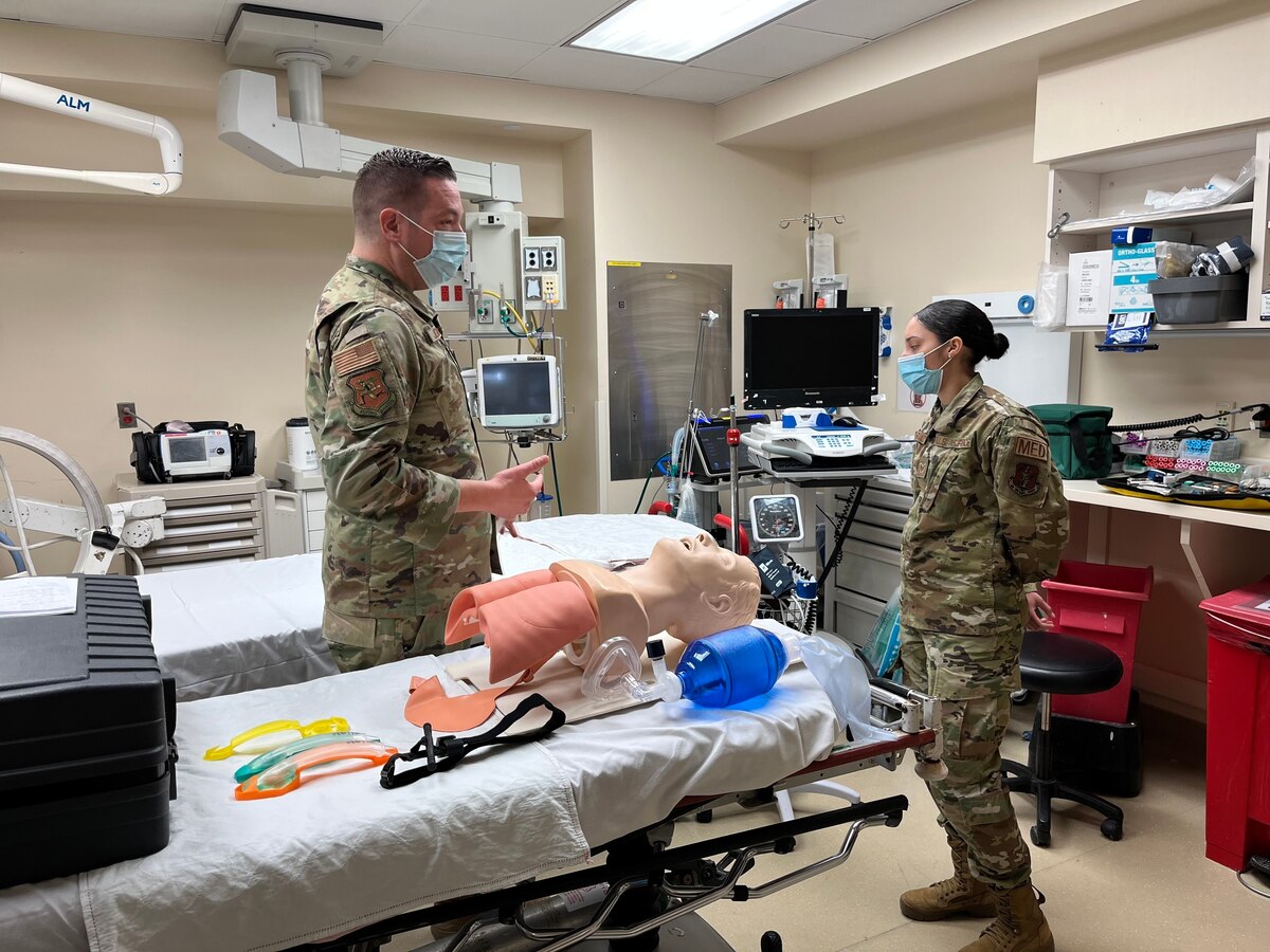 Image of two Airmen talking in an operating room.