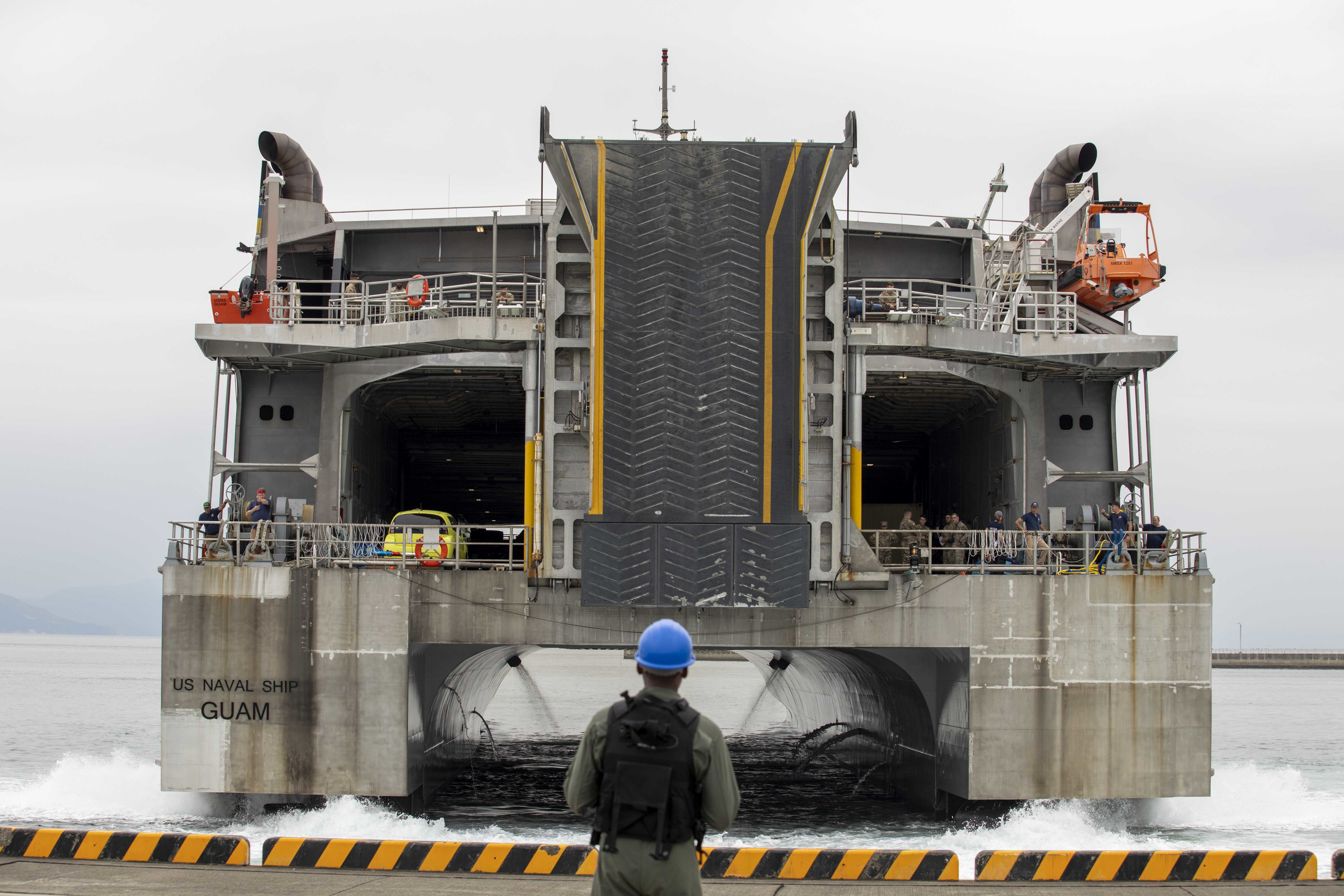 A U.S. Sailor assigned to Marine Corps Air Station Iwakuni watches as the Military Sealift Command high-speed transport vessel USNS Guam (T-HST-1) prepares to dock at MCAS Awakuni's harbor