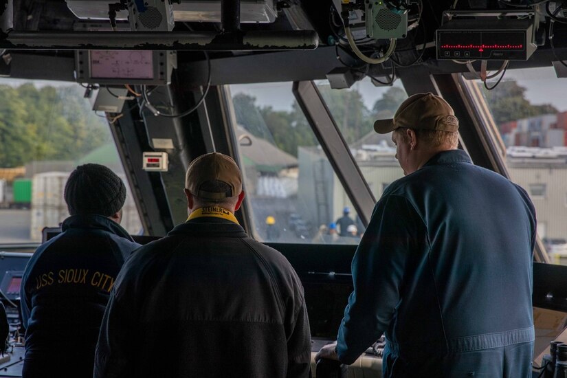 Sailors stand in the cabin of a ship.