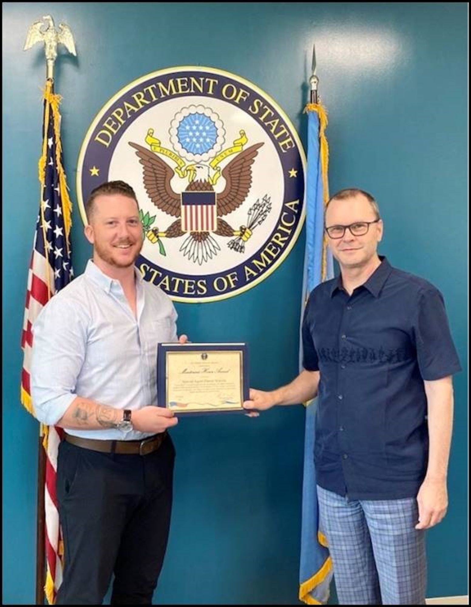 Andrew McLean, Charge' d'affaires, U.S. Embassy Koror, right, presents the U.S. State Department Meritorious Honor Award to Special Agent Daniel Scarola, OSI 6 FIR, SMB OL-A, Guam, Aug. 17, 2022. John Hennessy-Niland, U.S. Ambassador approved and signed the award before departing Palau to retire. (Photo by SA Nicole Orzech, OSI 6 FIR SMB OL-A, Guam.)