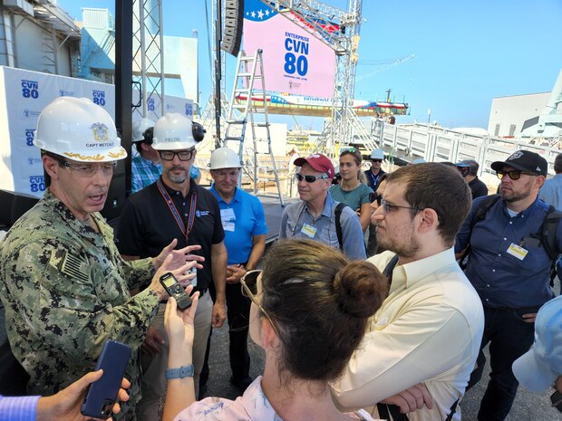 Capt. Brian Metcalf, Gerald R. Ford-Class New Construction Program Office addresses reporters questions during the future USS Enterprise (CVN 80) keel laying media availability at Huntington Ingalls, Newport News, Va., Aug. 26. Procuring CVN 80 and CVN 81 as part of a two-ship buy has already allowed us to realize efficiencies in the early construction process. And building the aircraft carrier with fewer, but larger, pre-outfitted super-lifts has been a major improvement that contributes to streamlining the construction of CVN 80 over previous Ford-class hulls.