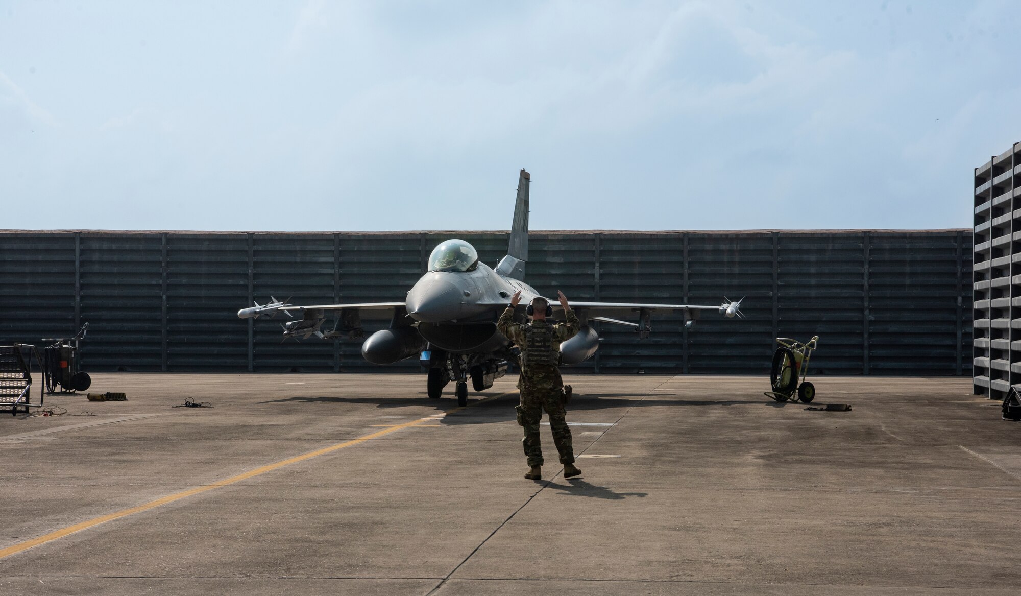 Tech. Sgt. Christopher Dial, a 51st Security Forces Squadron Airman, signals an F-16 Fighting Falcon during a training sortie at Gwangju Air Base, Republic of Korea, Aug. 18, 2022.