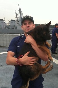 A photo of the dog "Lai Wong" who was aboard the Chinese Fishing Vessel BANGUN PERKASA that was seized by the crew of CGC MIDGETTE in 2012.  Lia Wong translates as Fortune Bringer.  He's being cared for in this photo by LT Nolan Cain, USCG.