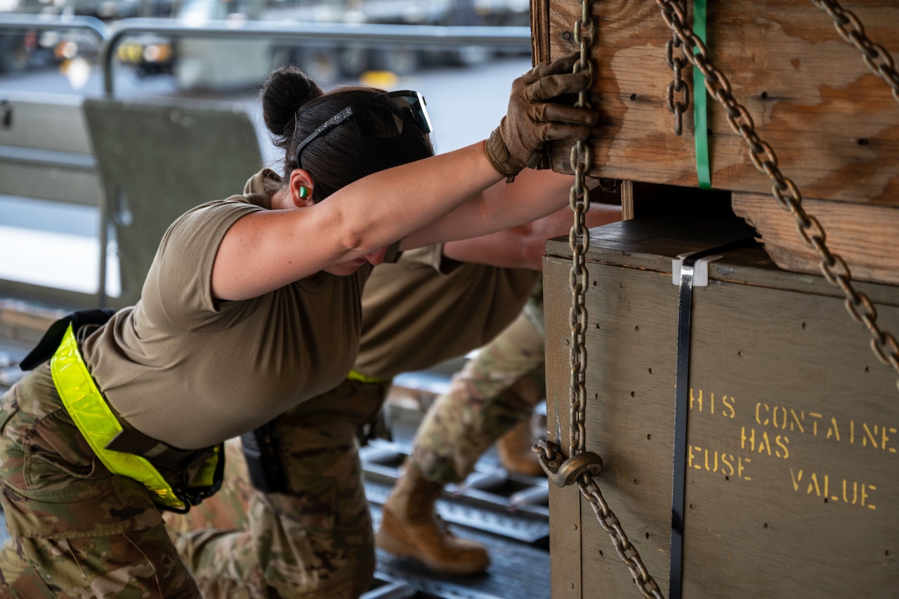 Airmen load pallets of weapons.