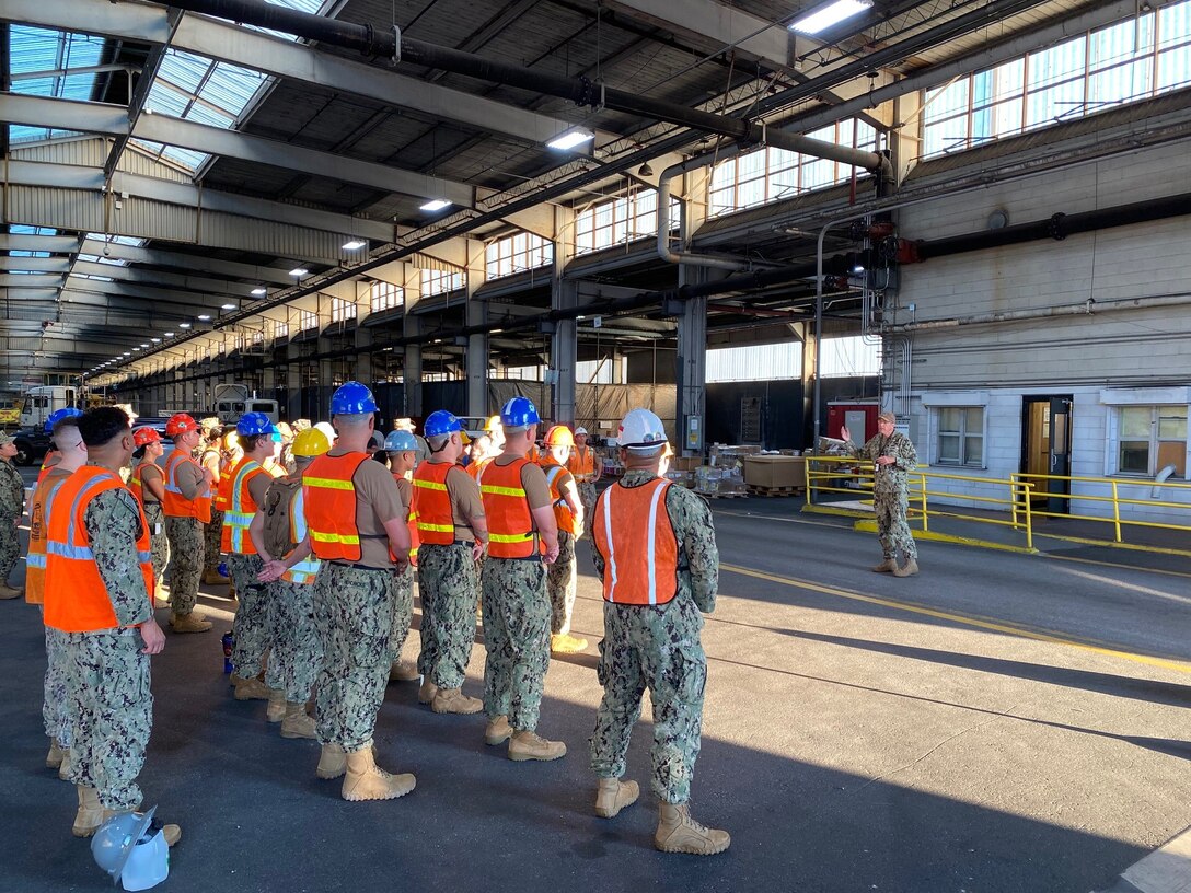 US Navy sailors standing in formation receiving a briefing