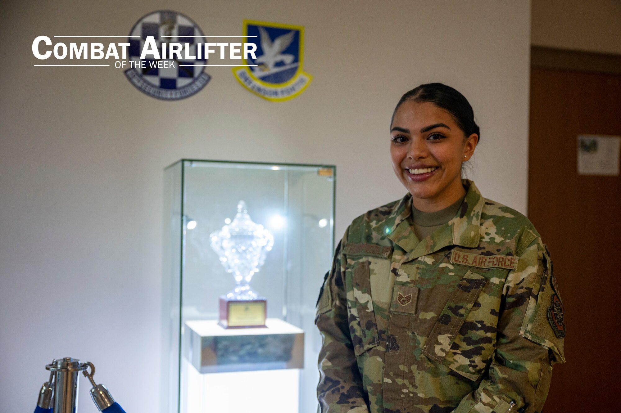 A woman poses for a photo in front of a trophy display case