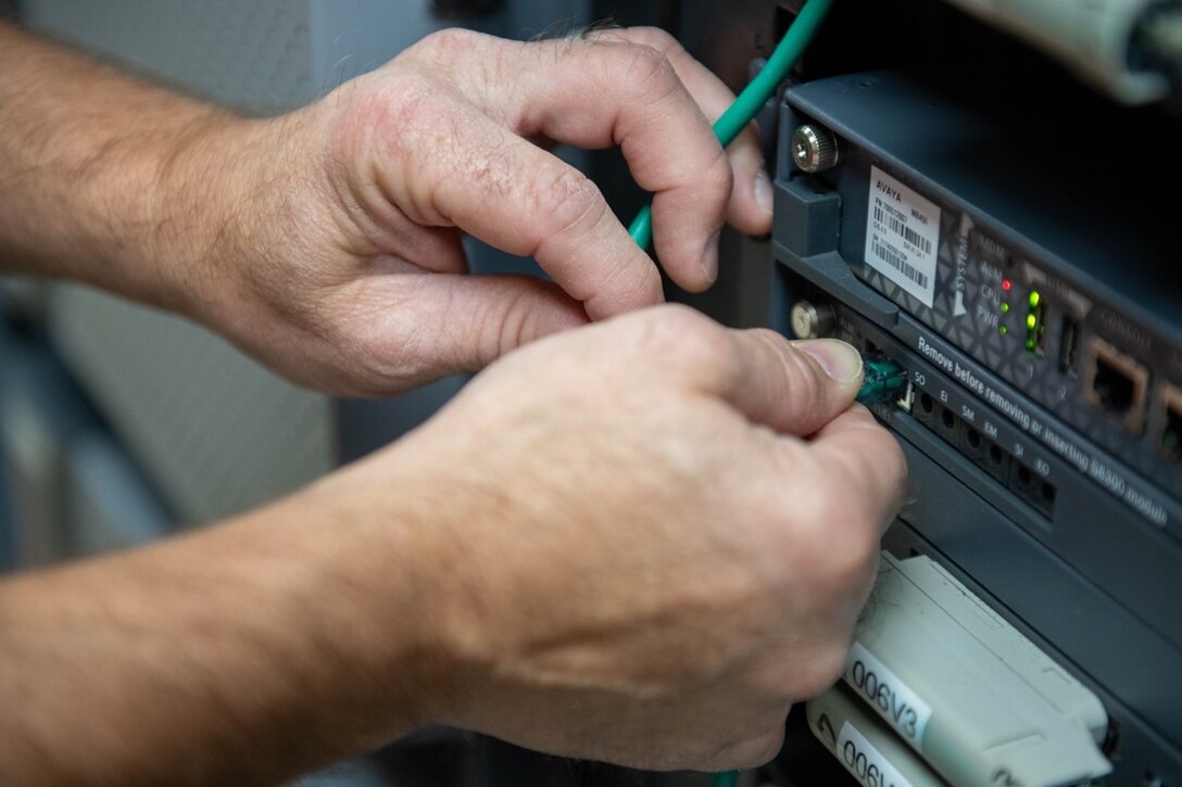 Rick Davis, 28th Communications Squadron telecommunications specialist, plugs a wire into a server at Ellsworth Air Force Base, S.D., Aug. 2, 2022.