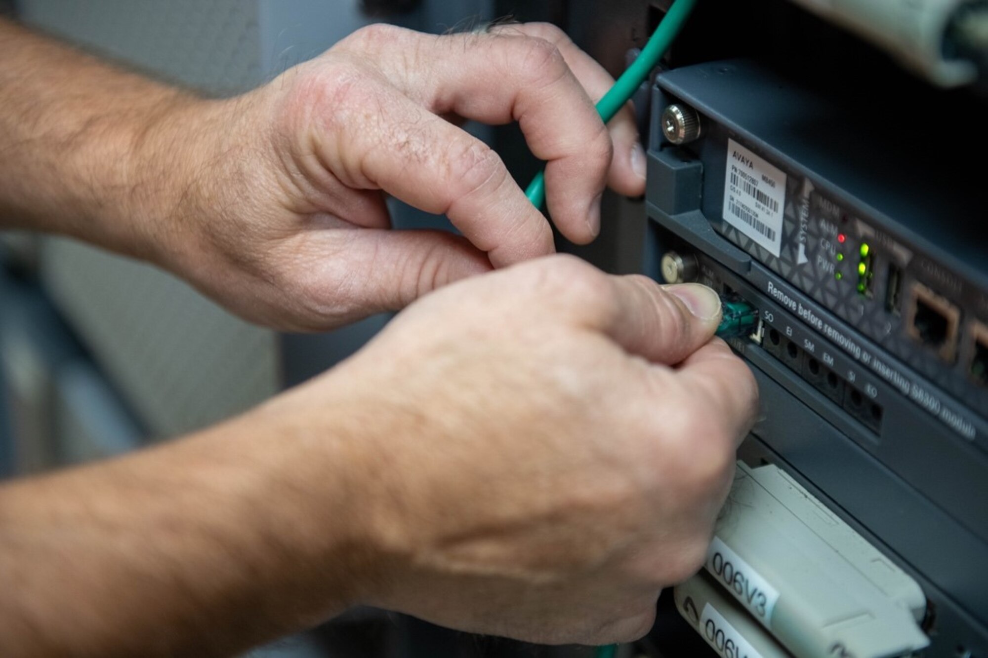 Rick Davis, 28th Communications Squadron telecommunications specialist, plugs a wire into a server at Ellsworth Air Force Base, S.D., Aug. 2, 2022.