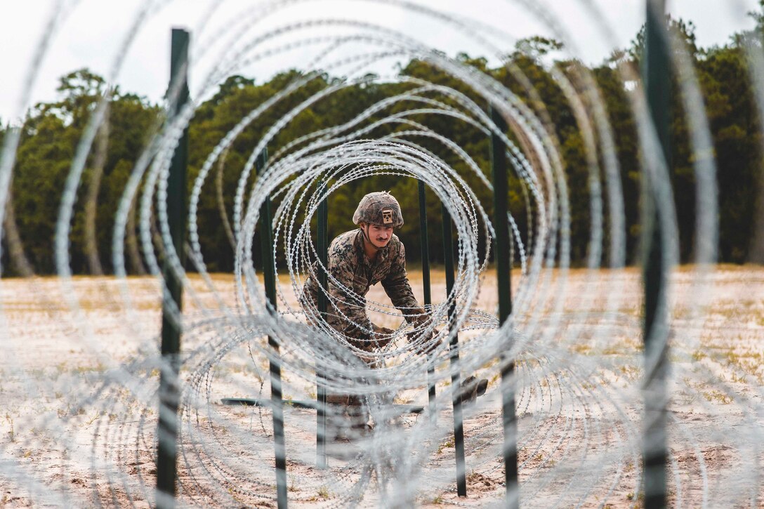 A Marine adjusts barbed wire.