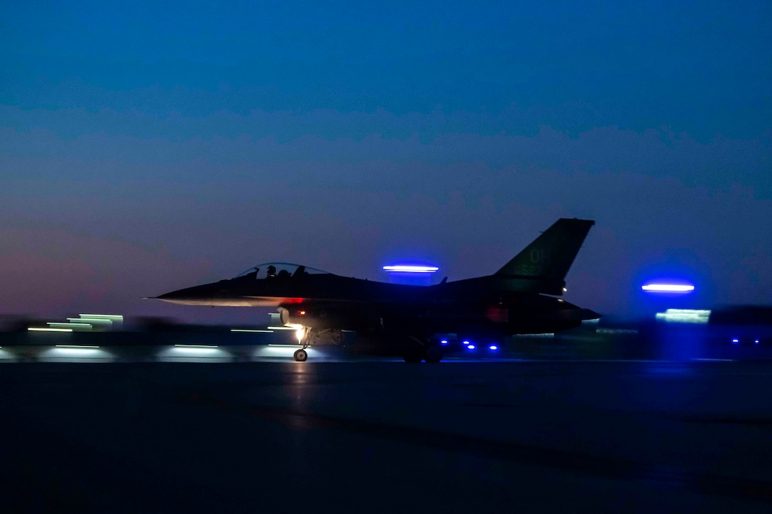 An aircraft takes off on a runway at night.