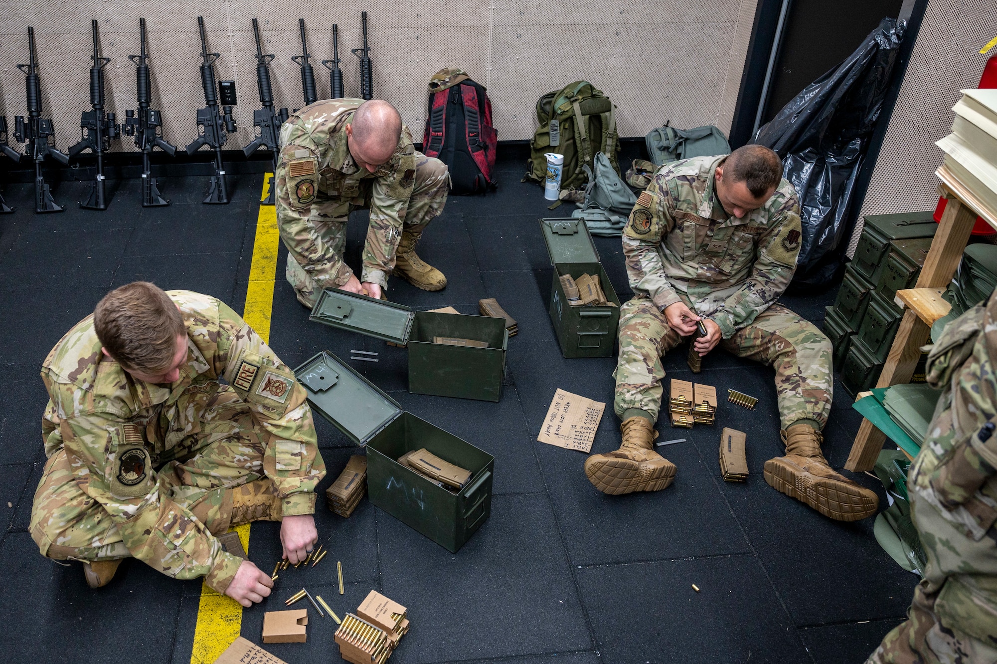 Men sitting on the floor loading rifle magazines
