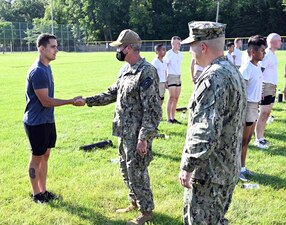 GREAT LAKES, Ill. (Aug. 24, 2022) Rear Adm. Pete Garvin, center, commander, Naval Education and Training Command, presents a coin to Navy Diver 1st Class Marcus Yensick, assigned to Center for Explosive Ordnance Disposal and Diving (CEODD), for his selection as CEODD’s Sailor of the year in Great Lakes, Illinois, Aug. 24, 2022. The learning site runs two courses of instruction for explosive ordnance disposal (EOD), Navy diver (ND) and diving medical technician (DMT) candidates.  The 18-day preparatory course is designed to prepare Sailors for EOD and ND “A” schools by providing training and mentoring in entry-level aquatic adaptability and physical and mental conditioning.  The 22-day Assessment and Selection Course is designed to prepare the most qualified EOD and ND candidates for a career in the Navy’s special operations community.  As the owner of the Force Development pillar within MyNavy HR, Garvin leads the NETC mission to recruit, train and deliver those who serve the nation, taking them from “street to fleet” by transforming civilians into highly skilled, operational and combat ready warfighters. (U.S. Navy photo by Matt Mogle)