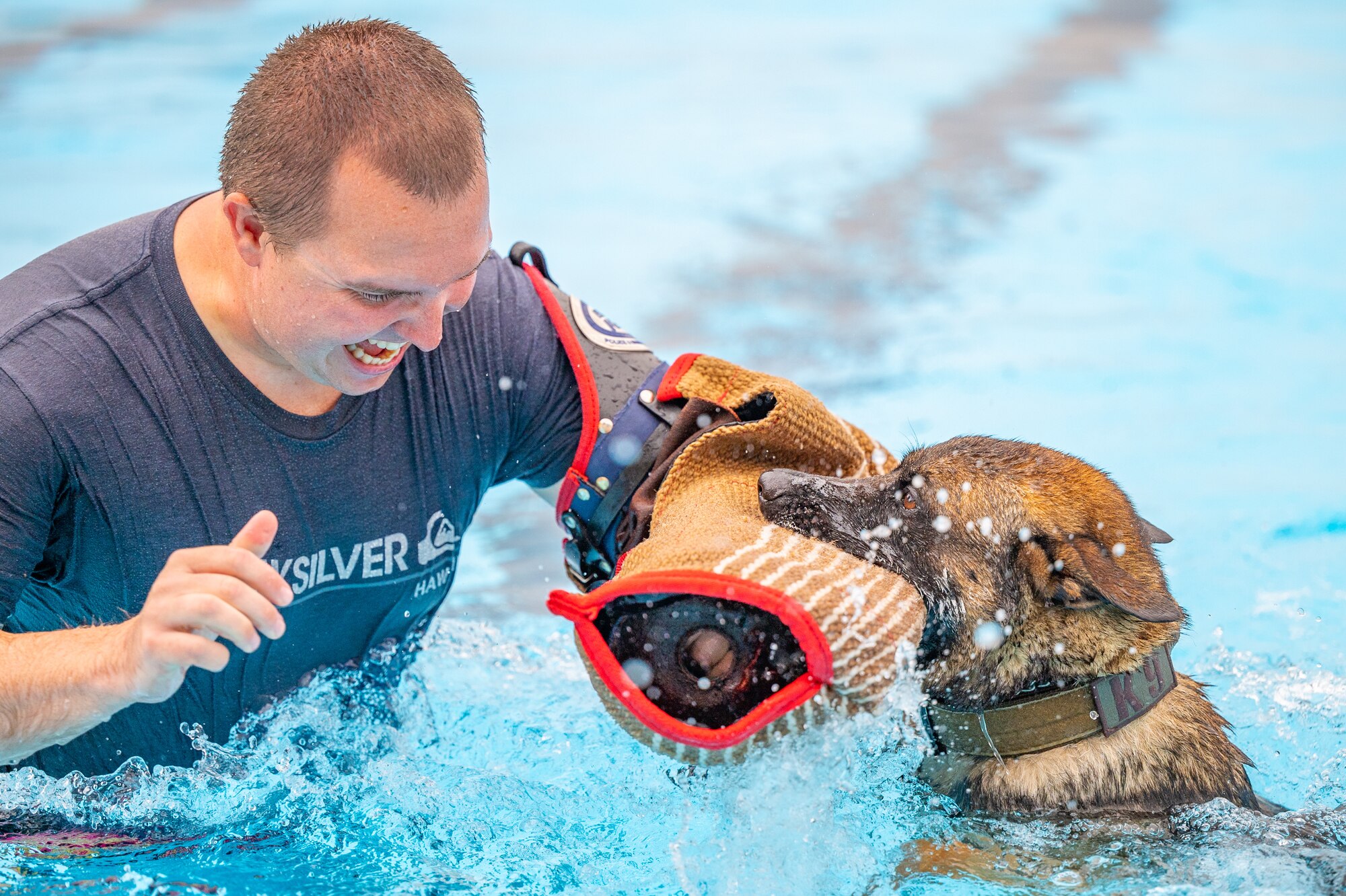 Bond, 341st Security Forces Squadron military working dog, clamps on to Staff Sgt. Christopher Hotine, 341st SFS military working dog handler, Aug. 24, 2022, at Malmstrom Air Force Base, Mont. The K-9’s have their annual water-training on the final day the base pool is filled, because water-training is an essential part of teaching the MWD’s how to adapt to new environments. (U.S. Air Force photo by Airman 1st Class Mary Bowers)