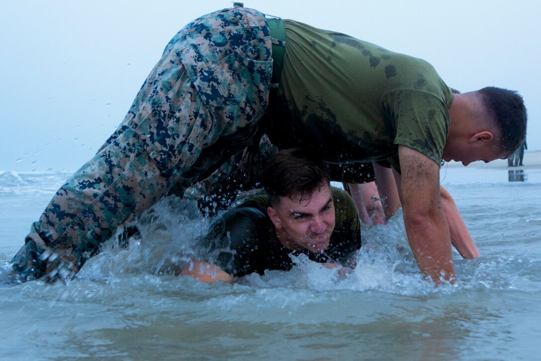 U.S. Marine Corps Cpl. student with Headquarters and Support Battalion's Corporals Course 4-22, crawls under his squad during a physical training exercise at Del Mar Beach on Marine Corps Base Camp Pendleton, California, Aug. 16, 2022. Corporals Course provides Marines with the skills and knowledge necessary to become successful small-unit leaders. (U.S. Marine Corps photo by Lance Cpl. Espitia)