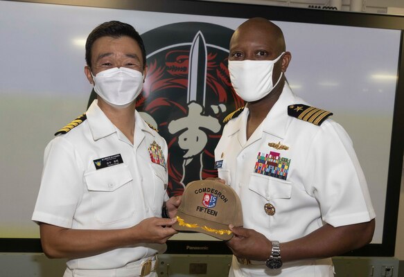 Capt. Walter Mainor, commander, Task Force 71, presents a gift to Japan Maritime Self-Defense Force (JMSDF) Capt. Hiroaki Tanaka, exercise director/Commander-in-Chief Self-Defense Fleet, during the opening ceremony for Pacific Vanguard (PV) 22-1 held aboard JMSDF helicopter destroyer JS Izumo (DDH 183) pierside at Naval Base Guam, Aug. 25. PV 22-1 is an exercise with a focus on interoperability and the advanced training and integration of allied maritime forces.