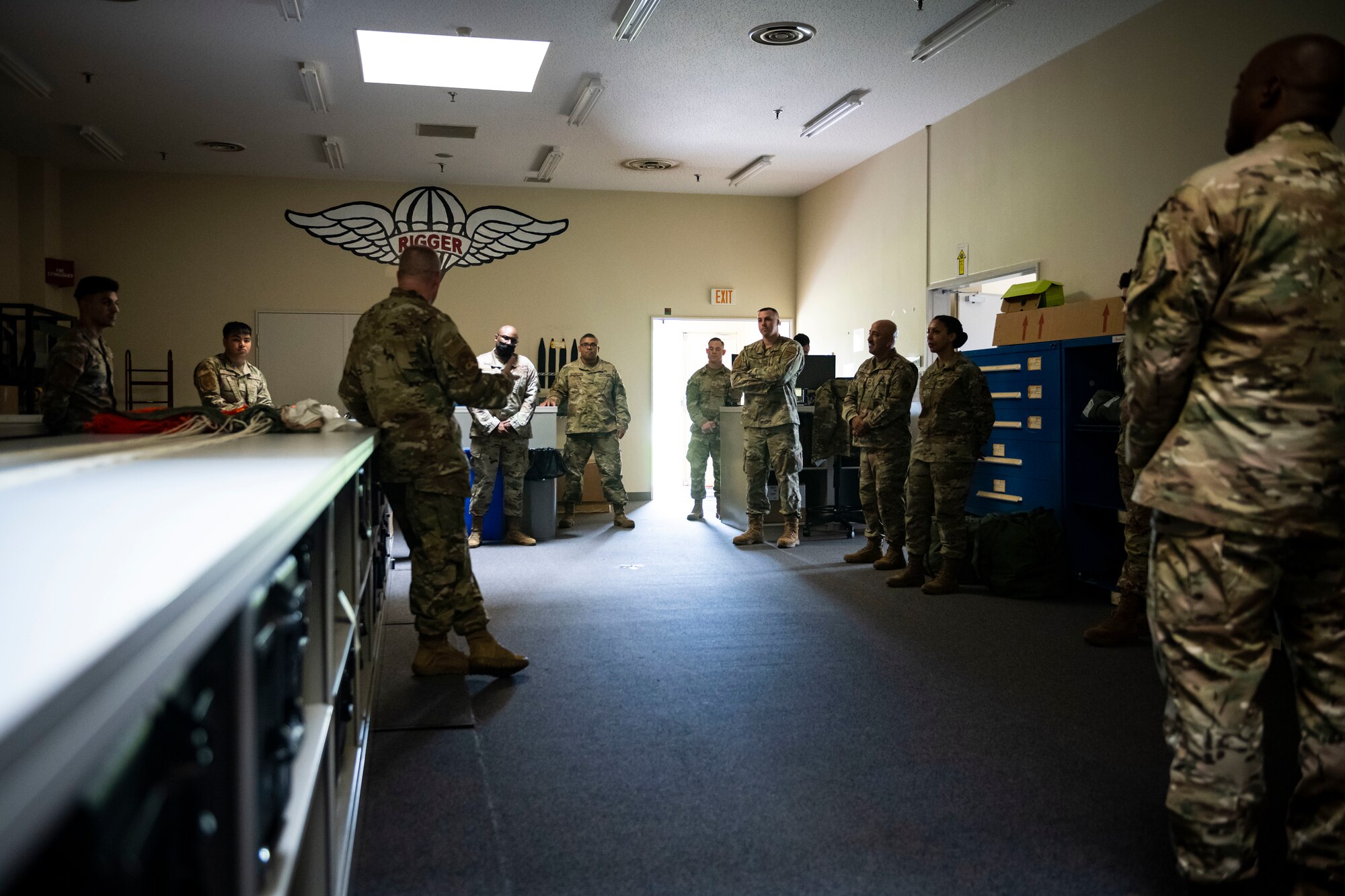 U.S. military members in uniform stand in room talking.