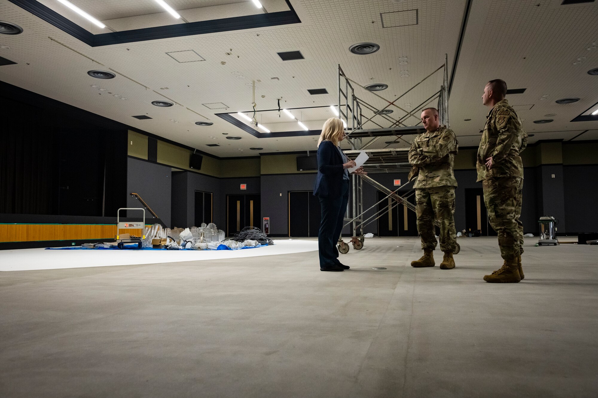 U.S. military members in uniform and civilians talk in an empty room under construction.