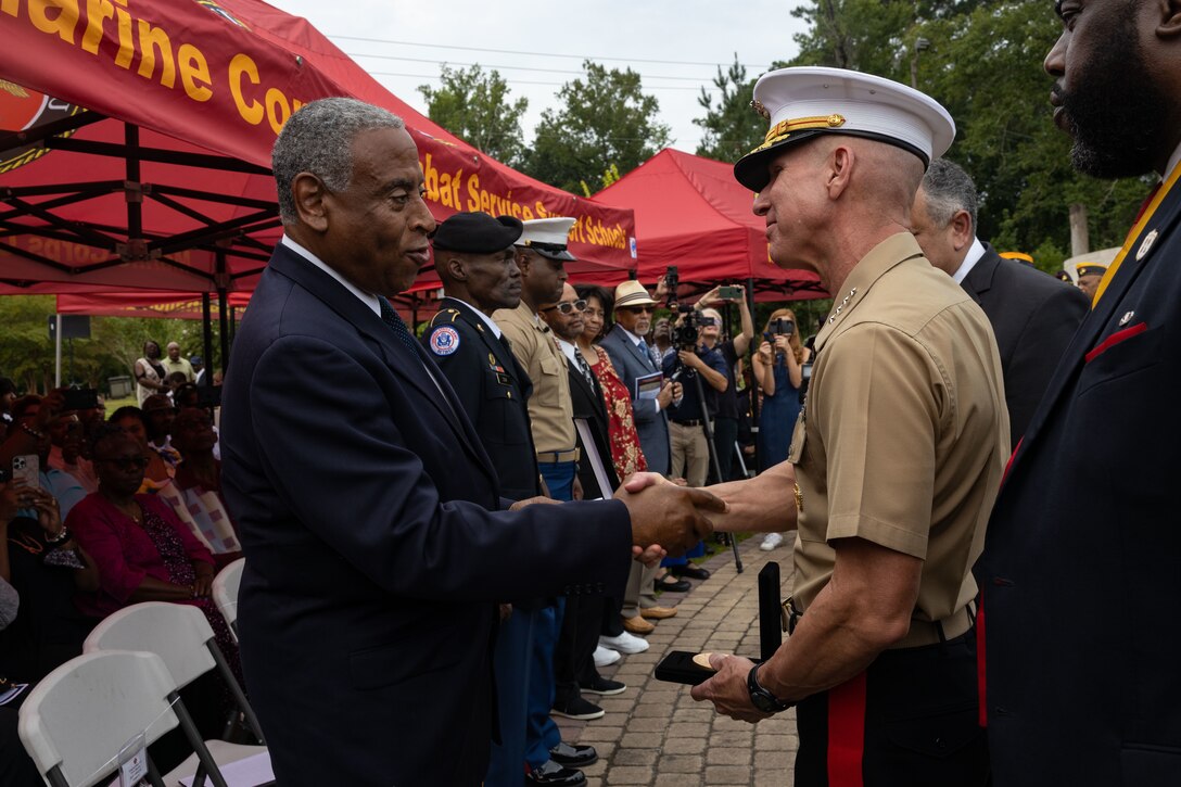 U.S. Marine Corps Gen. Eric M. Smith, assistant commandant of the Marine Corps, awards the Congressional Gold Medal to Joseph Banks Jr. who accepted the award on behalf of his father, retired U.S. Marine Corps Sgt. Maj. Joseph L. Banks, during the 13th Annual Montford Point Marine Day Ceremony at the Lejeune Memorial Gardens in Jacksonville, North Carolina, Aug. 25, 2022. The annual Montford Point Marine Day Ceremony honors the first African Americans to serve in the United States Marine Corps and recognizes their accomplishments, sacrifices and dedication to our country. (U.S. Marine Corps photo by Cpl. Makayla Elizalde)