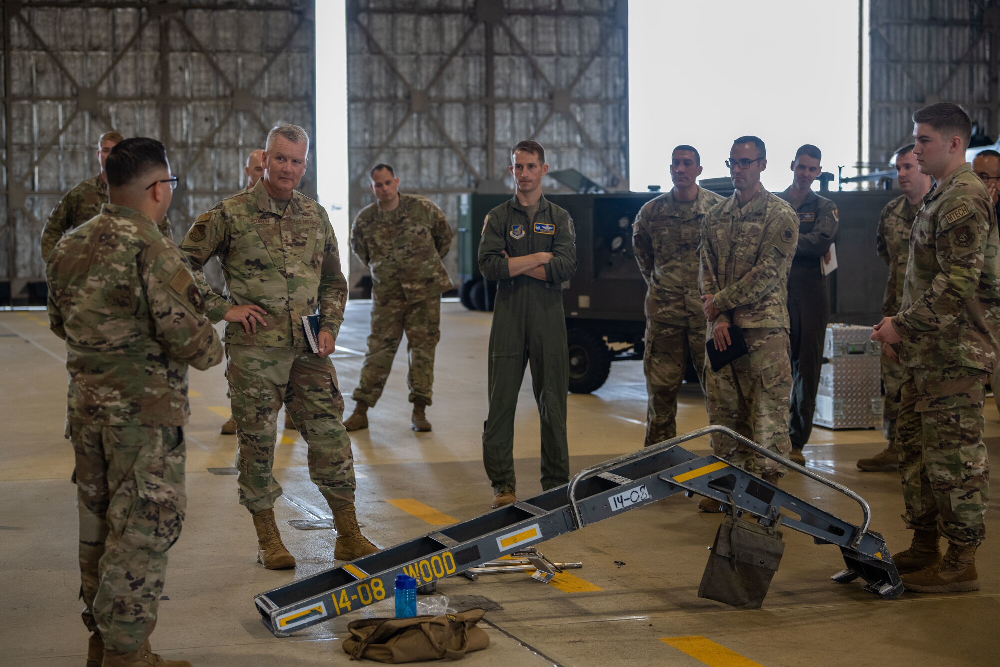 U.S. military members stand around an F-16 ladder and talk.