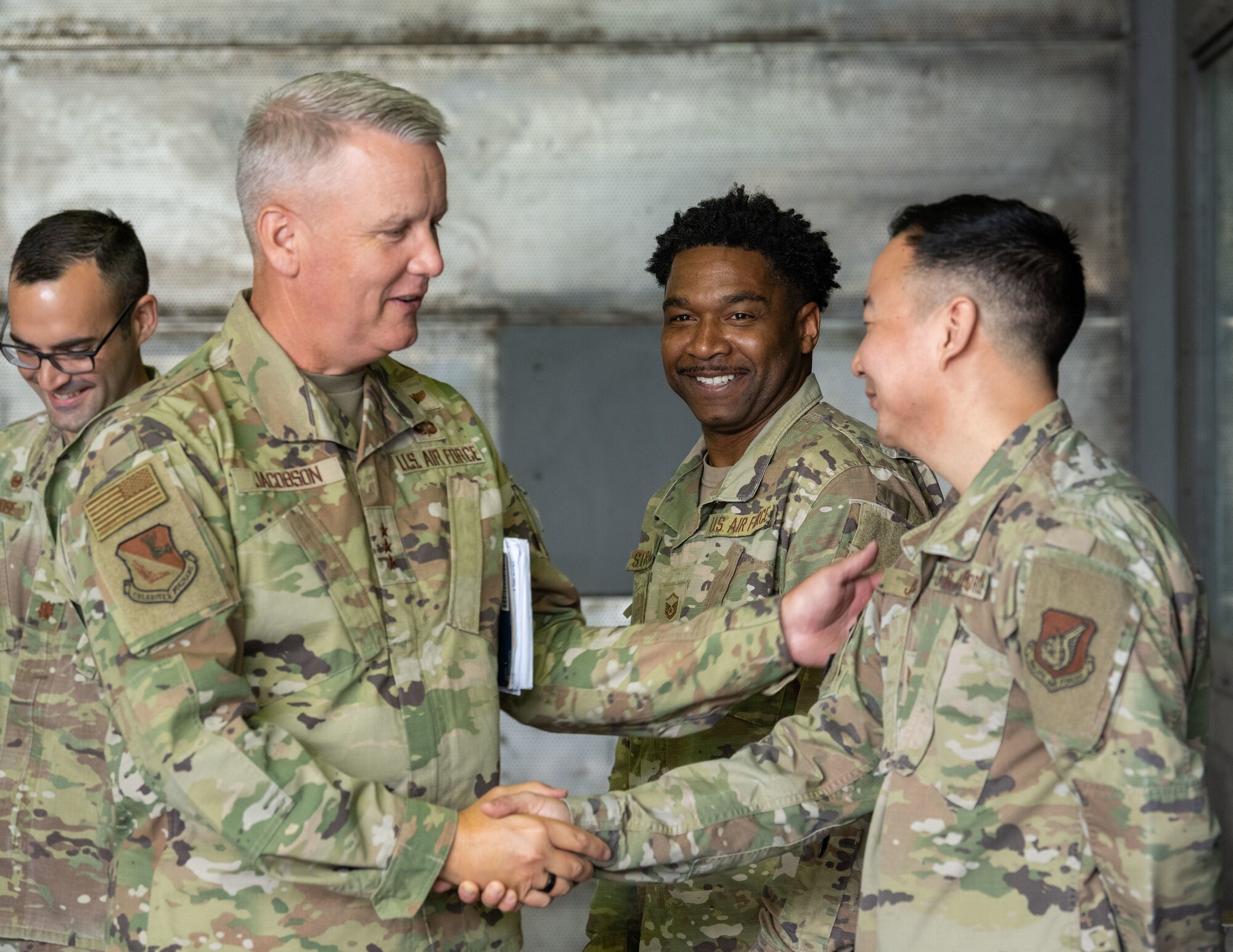 U.S. military members in uniform shake hands while talking to each other.