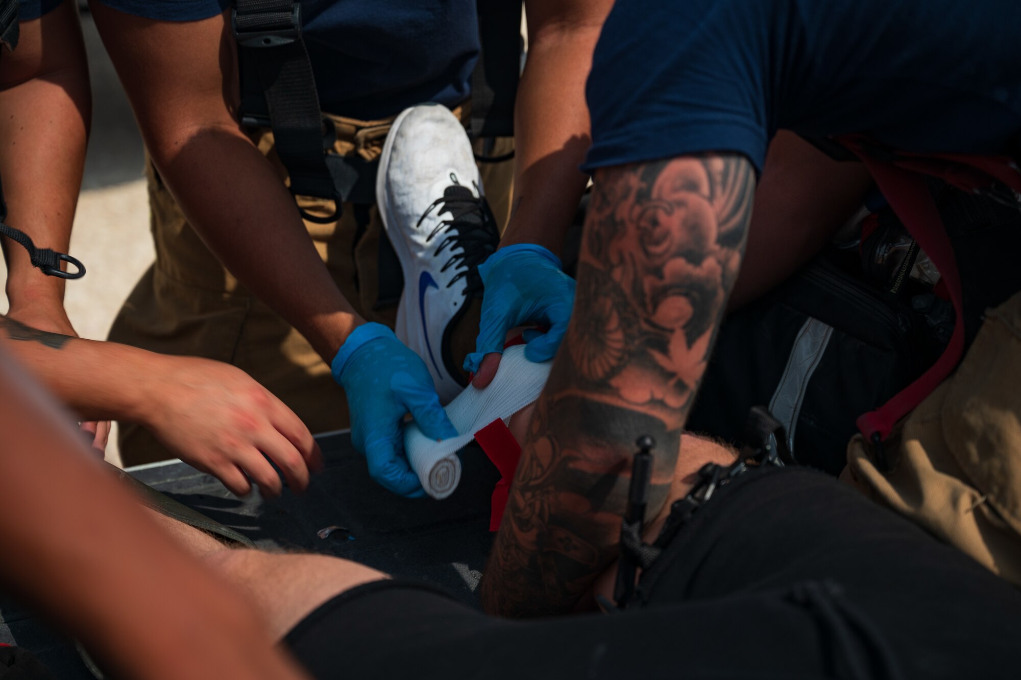 U.S. Air Force firefighters from 379th Expeditionary Civil Engineer Squadron provide basic on scene medical support to Senior Airman Colton Kelly, a fellow firefighter with simulated blast wounds during an exercise Aug. 24, 2022 at Al Udeid Air Base, Qatar. Kelly had simulated wounds from stepping on an explosive ordnance during an exercise. (U.S. Air Force photo by Staff Sgt. Dana Tourtellotte)