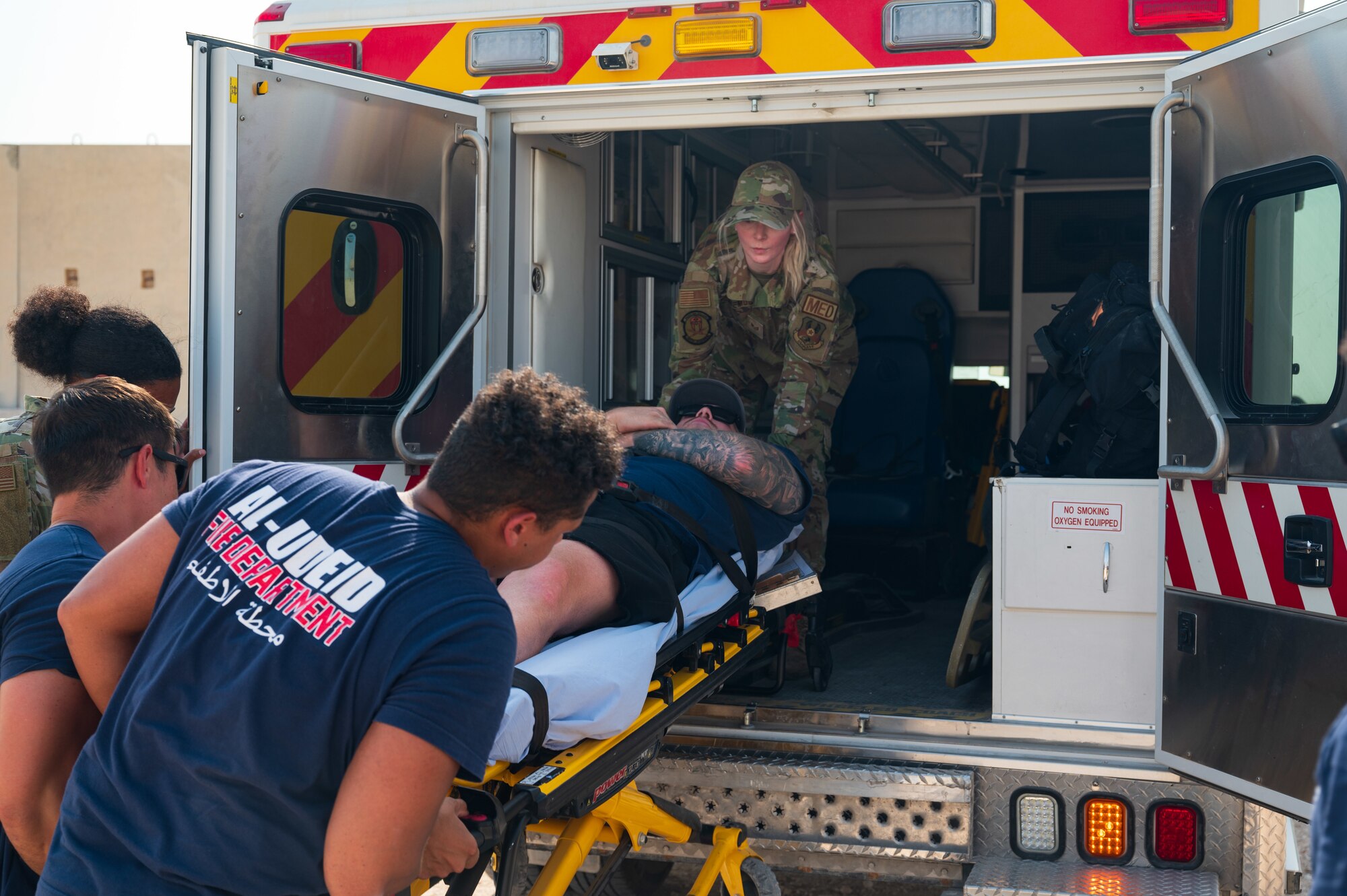 U.S. Air Force firefighters, in unison with USAF paramedics from the 379th Air Expeditionary Wing, simulate recovering wounded firefighter Senior Airman Colton Kelly during an exercise Aug. 24, 2022 at Al Udeid Air Base, Qatar. Colton had simulated wounds from stepping on explosive ordnance during an exercise. (U.S. Air Force photo by Staff Sgt. Dana Tourtellotte)